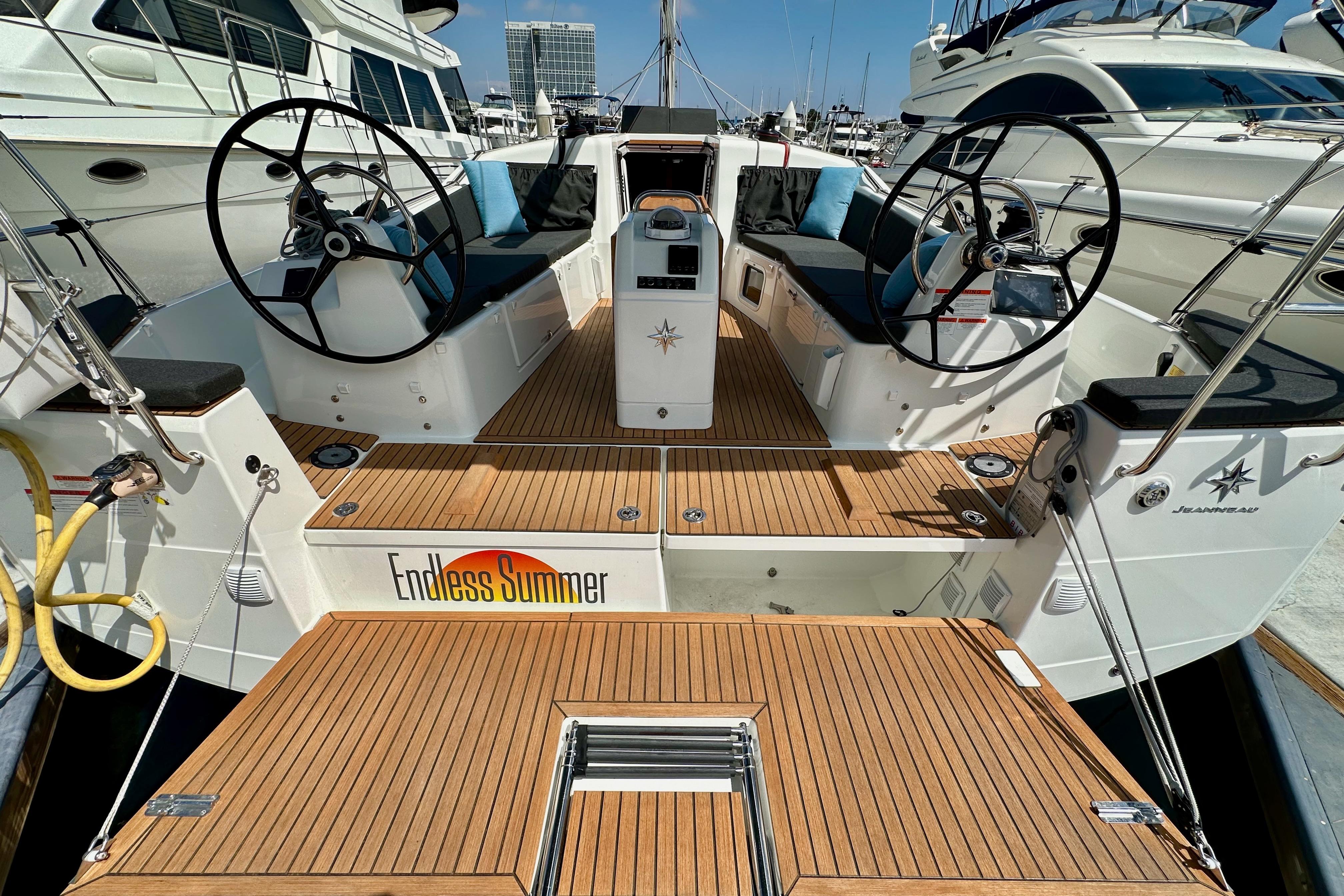 2024 Jeanneau Sun Odyssey 410 yacht with dual steering wheels and teak deck, docked in marina.