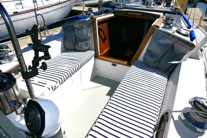 1989 Catalina 34 sailboat cockpit with striped cushions and wooden hatch.
