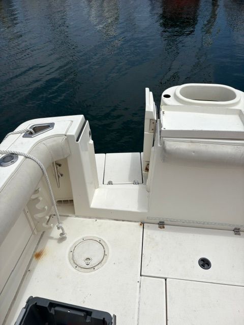 The boat features a white deck with seating and rope, docked by the water.