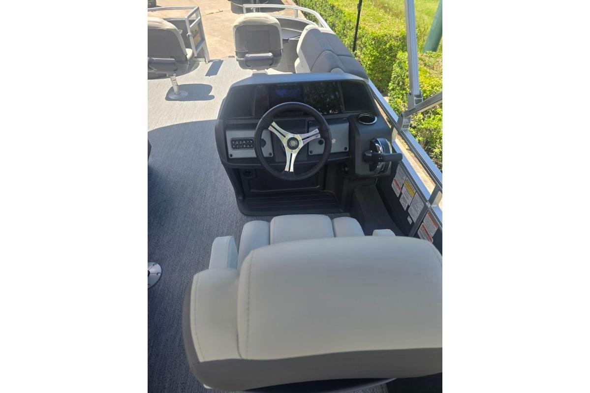 2026 Sun Tracker Fishin' Barge 22 DLX helm with steering wheel and seating.