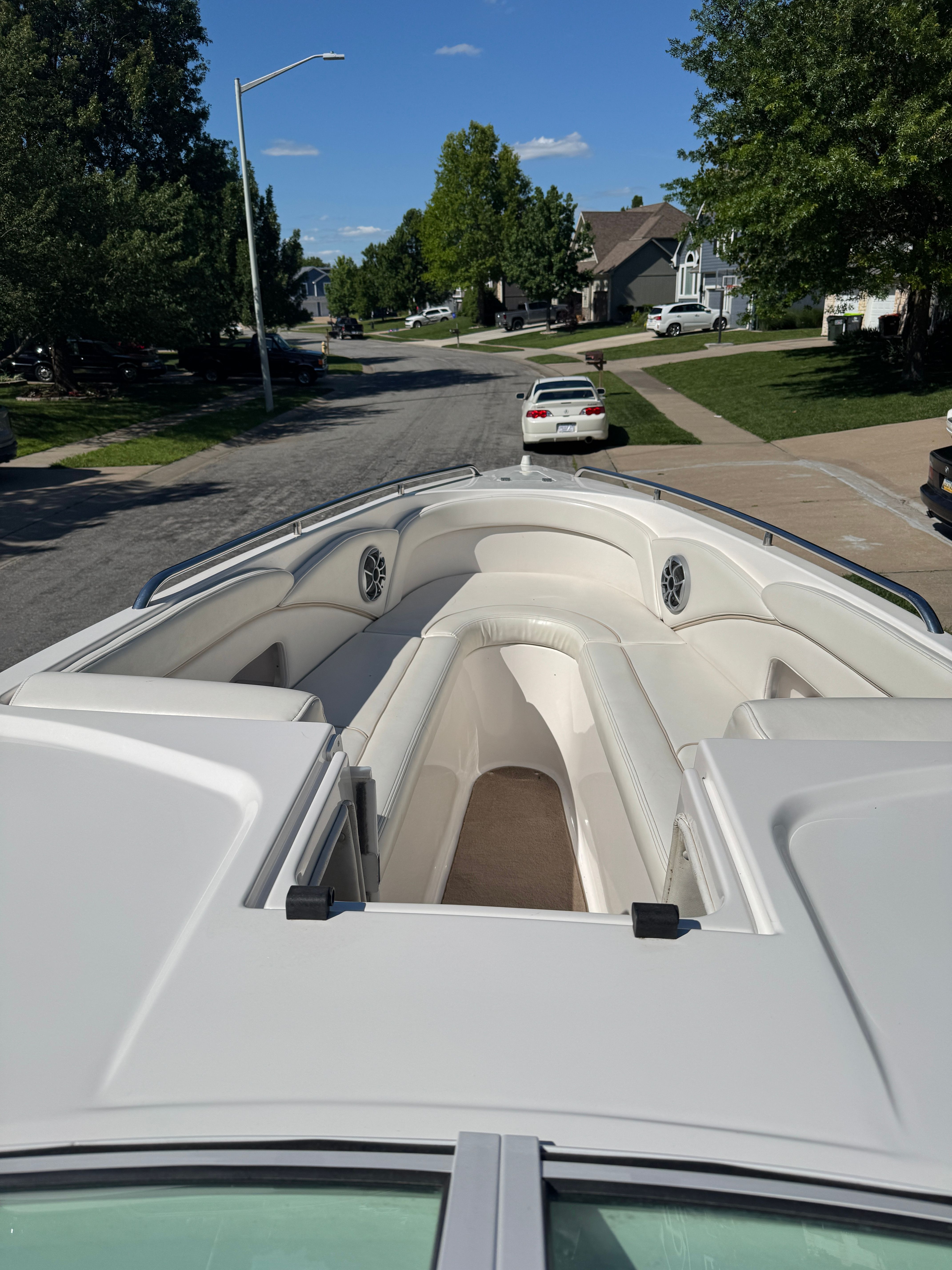 The image shows the bow of a boat with white upholstery, parked on a street.