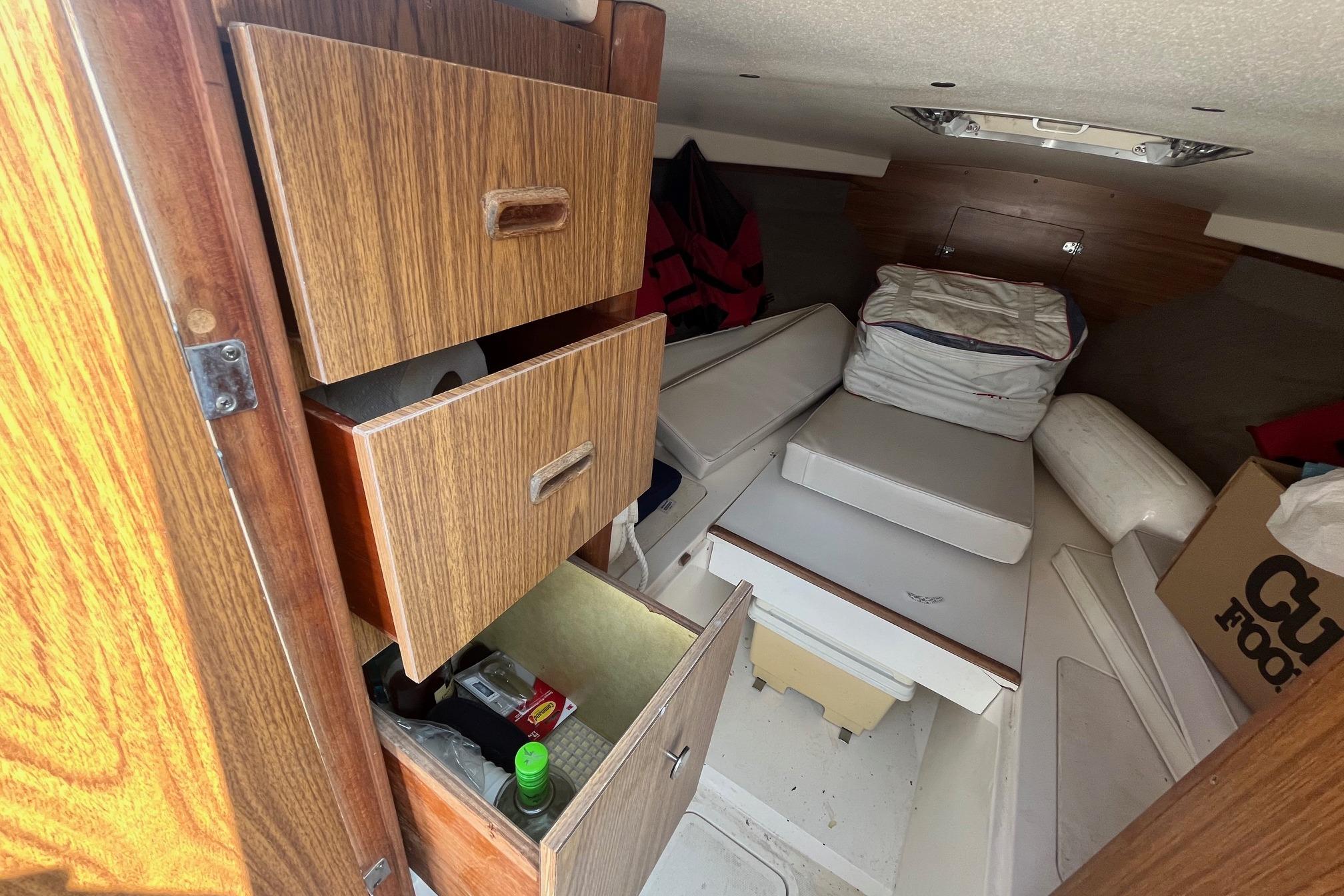 Interior of a 1975 Bertram 26 Moppie boat with wooden cabinets and cushions.