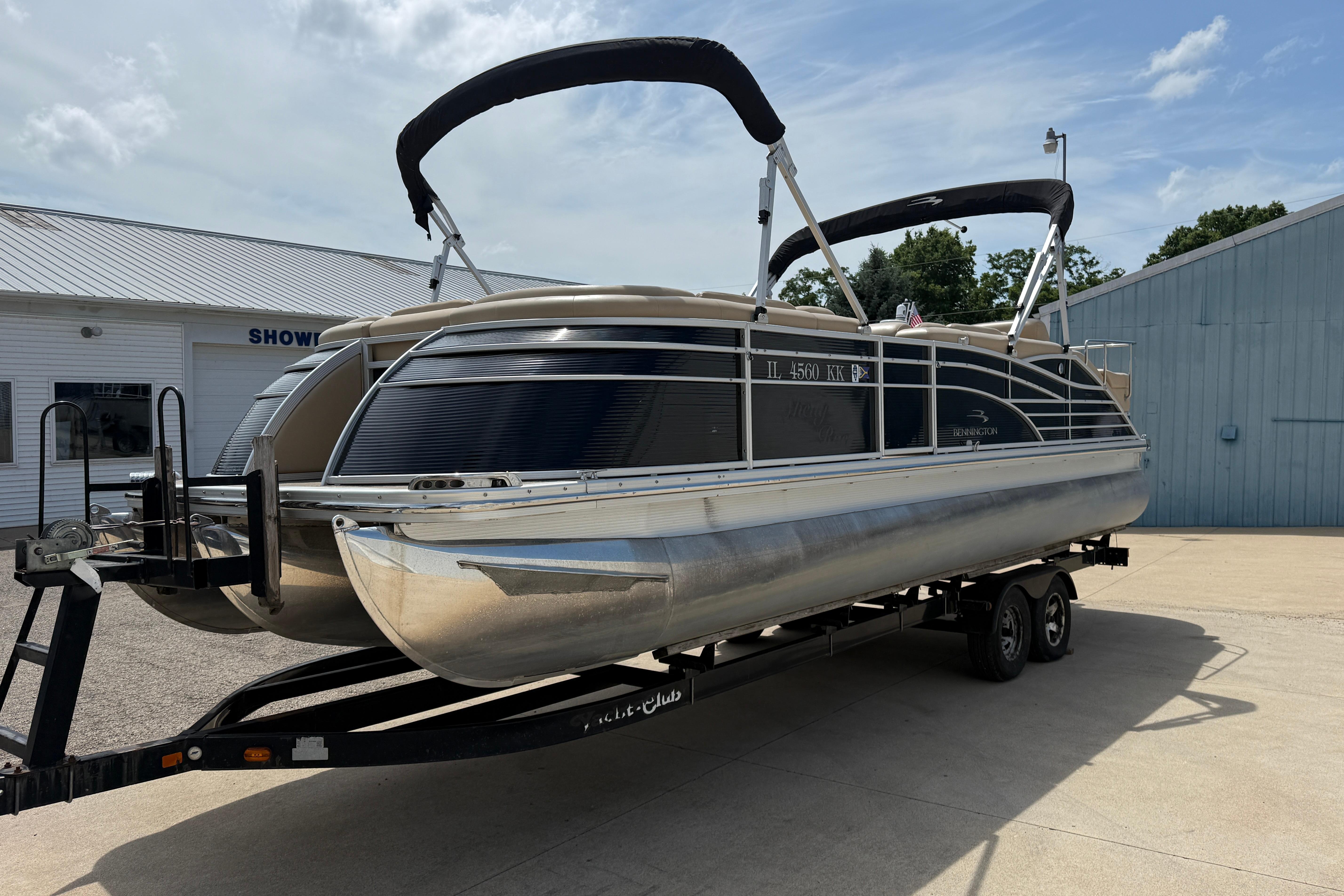 2011 Bennington 2575QCW I/O pontoon boat on trailer, parked outside a showroom.