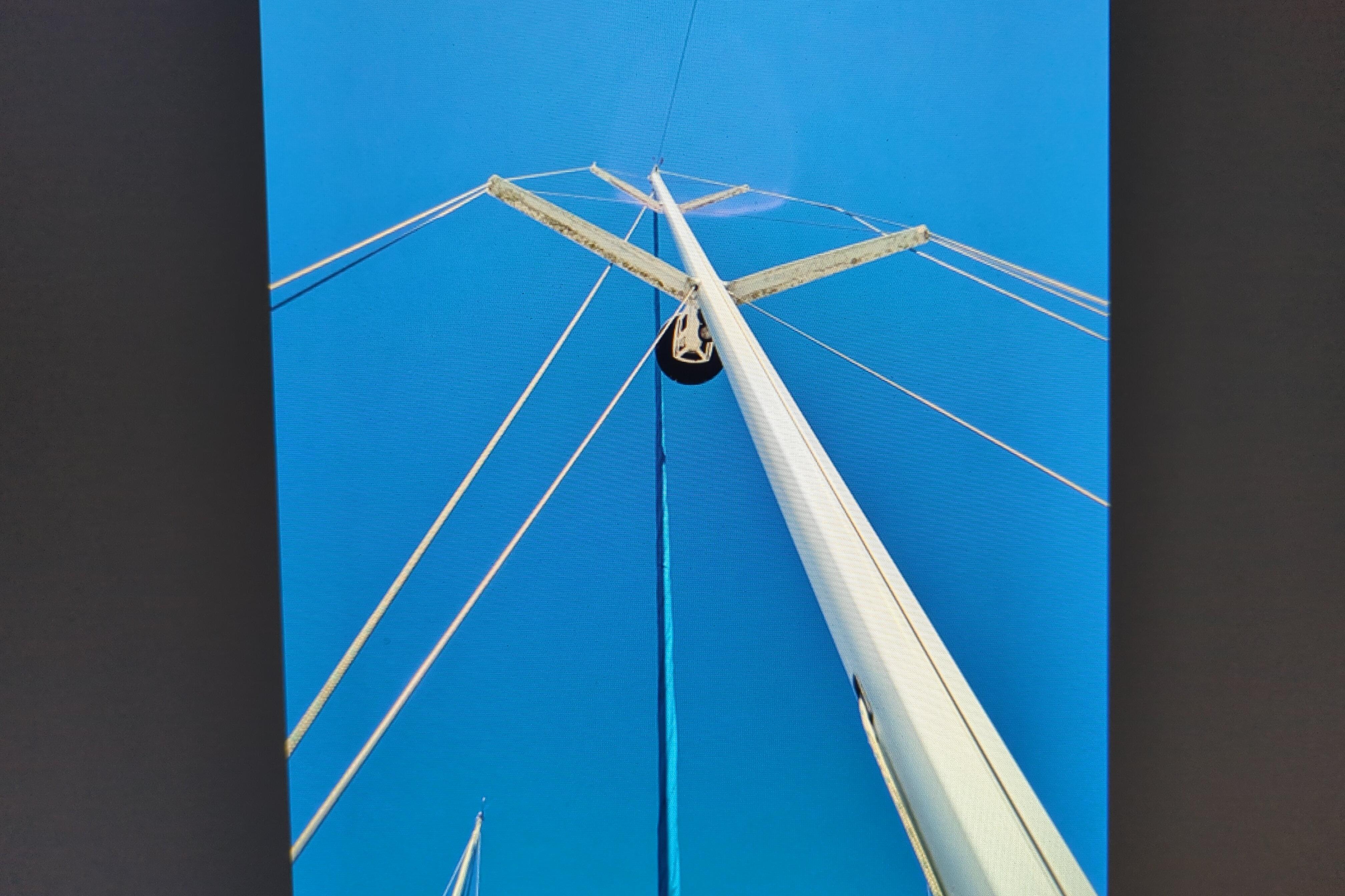 Looking up at the mast of a 1990 Catalina 42 sailboat against a clear blue sky.