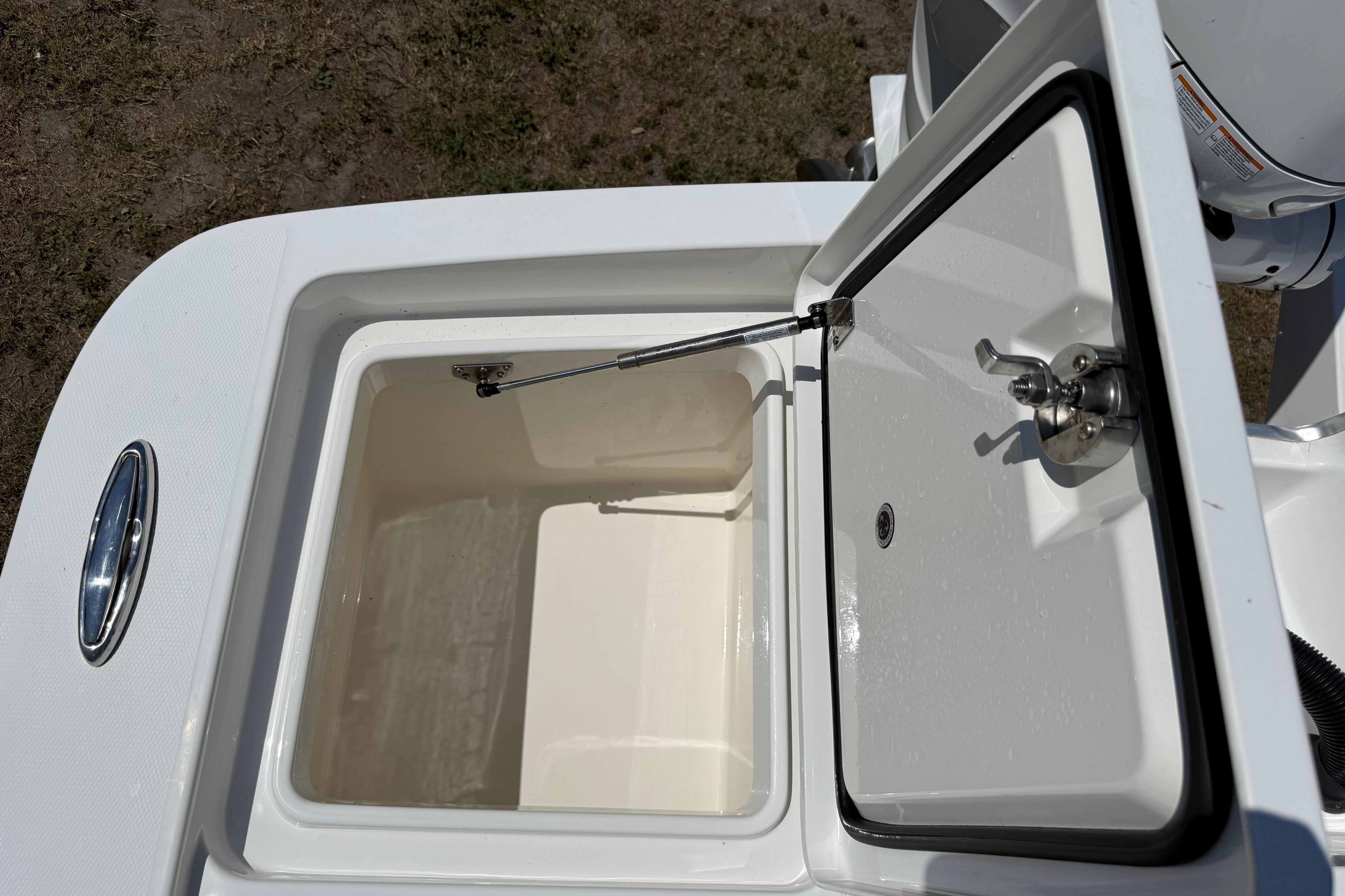 Open storage compartment on 2023 Regulator 26XO boat, showcasing interior design and latch mechanism.