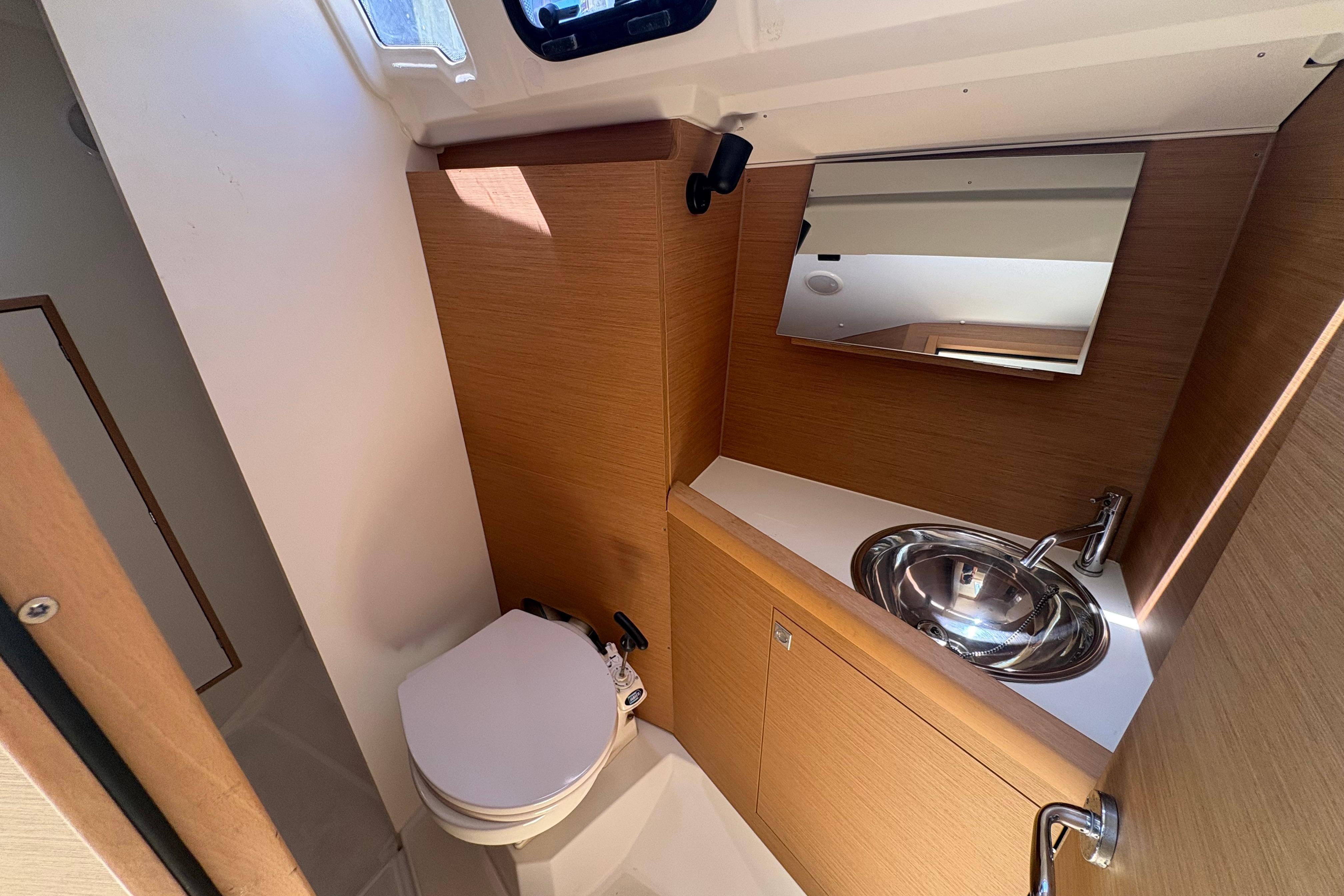 Modern bathroom interior of 2021 Jeanneau Sun Odyssey 349 yacht with sink and toilet.