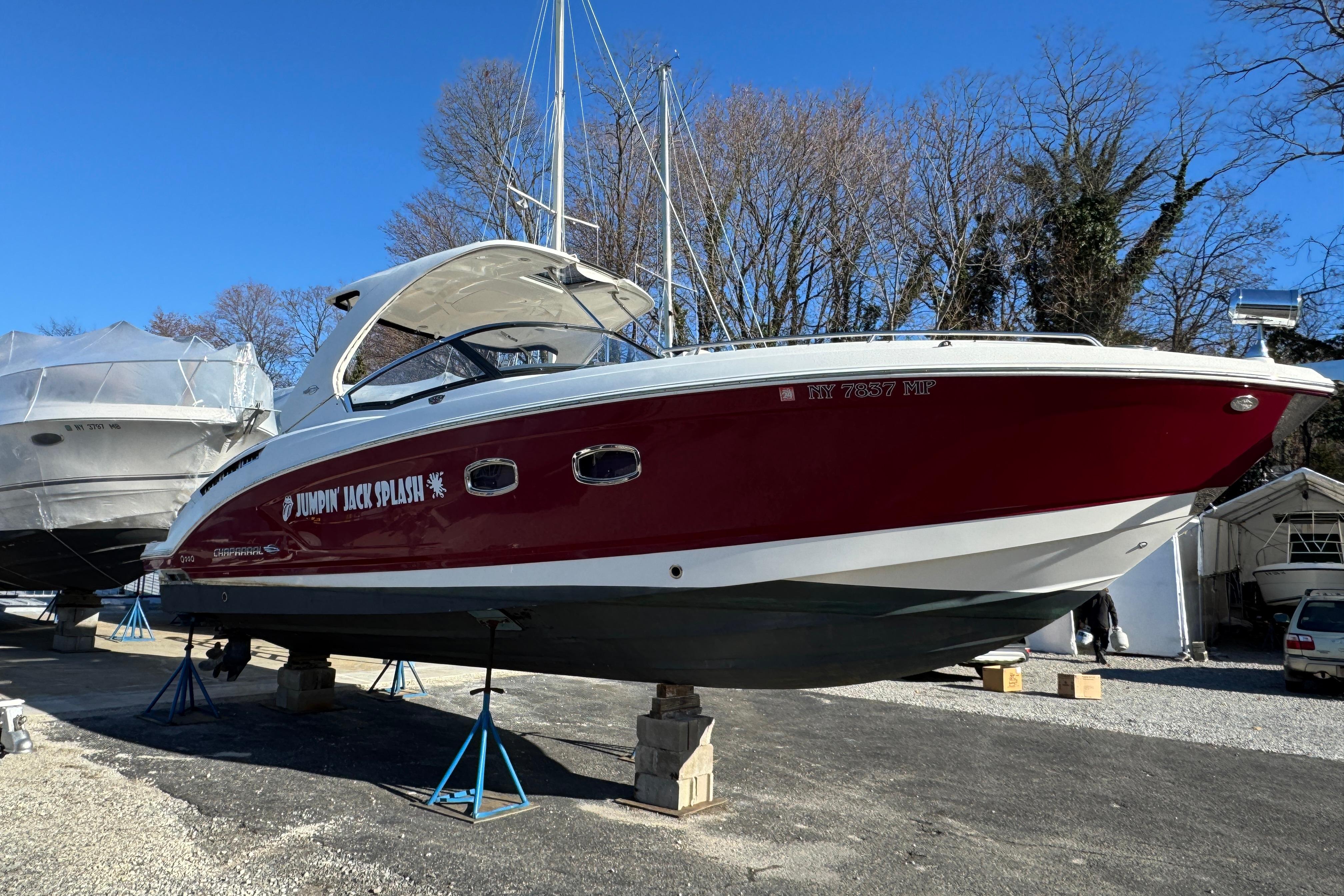 2012 Chaparral 327 SSX boat in dry dock, red hull, clear sky background.