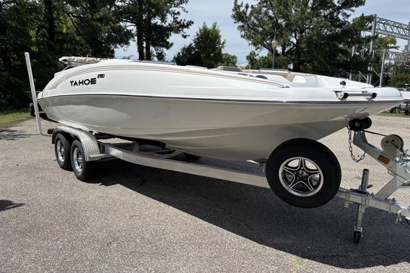 2026 Tahoe 2150 boat on trailer, parked outdoors, surrounded by trees.