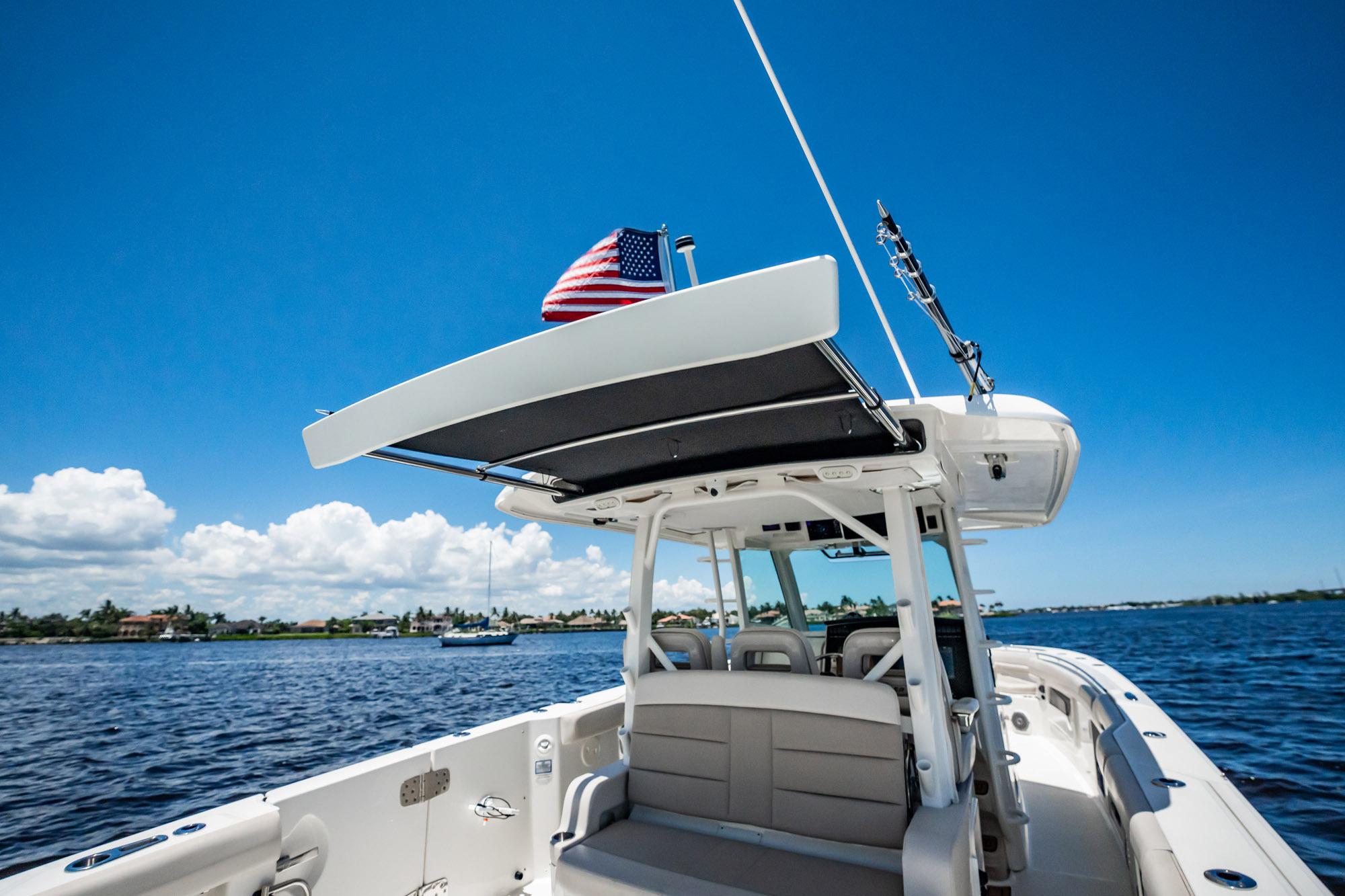 2018 Boston Whaler 380 Outrage boat on water, clear sky, American flag flying.