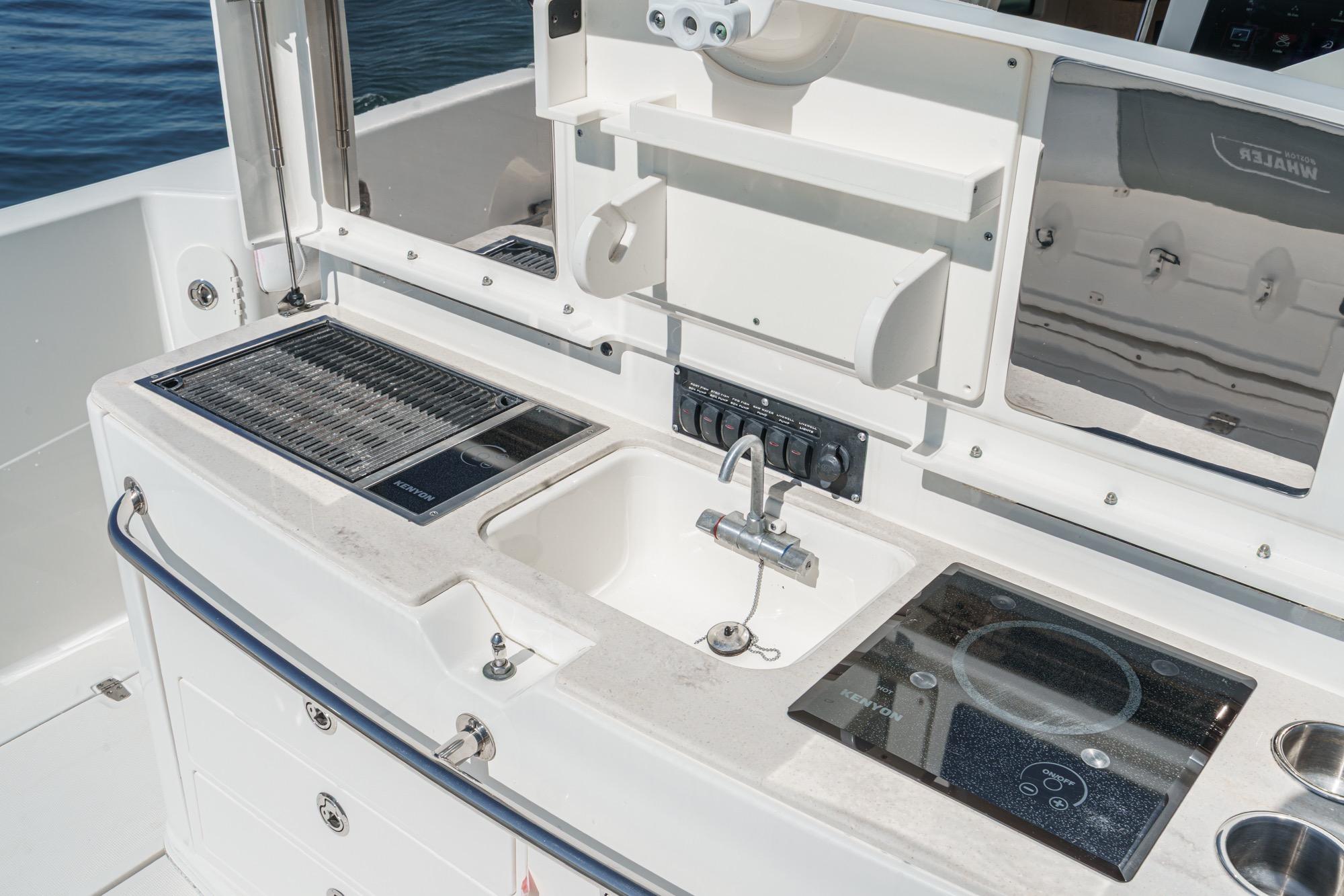 2015 Boston Whaler 370 Outrage boat kitchen with grill, sink, and stove.