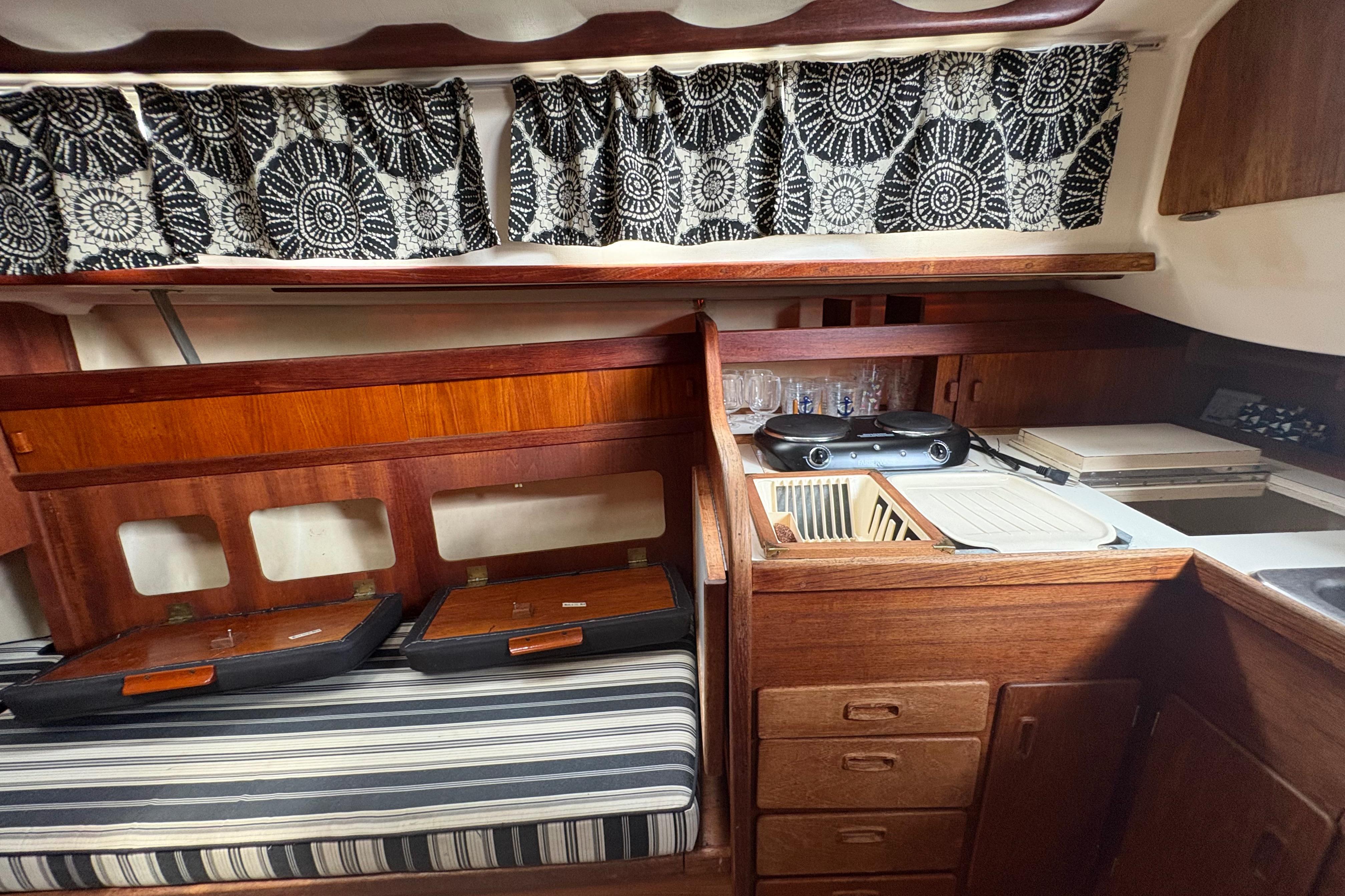 Interior of a 1981 Sabre 31 sailboat with wood cabinetry and patterned curtains.