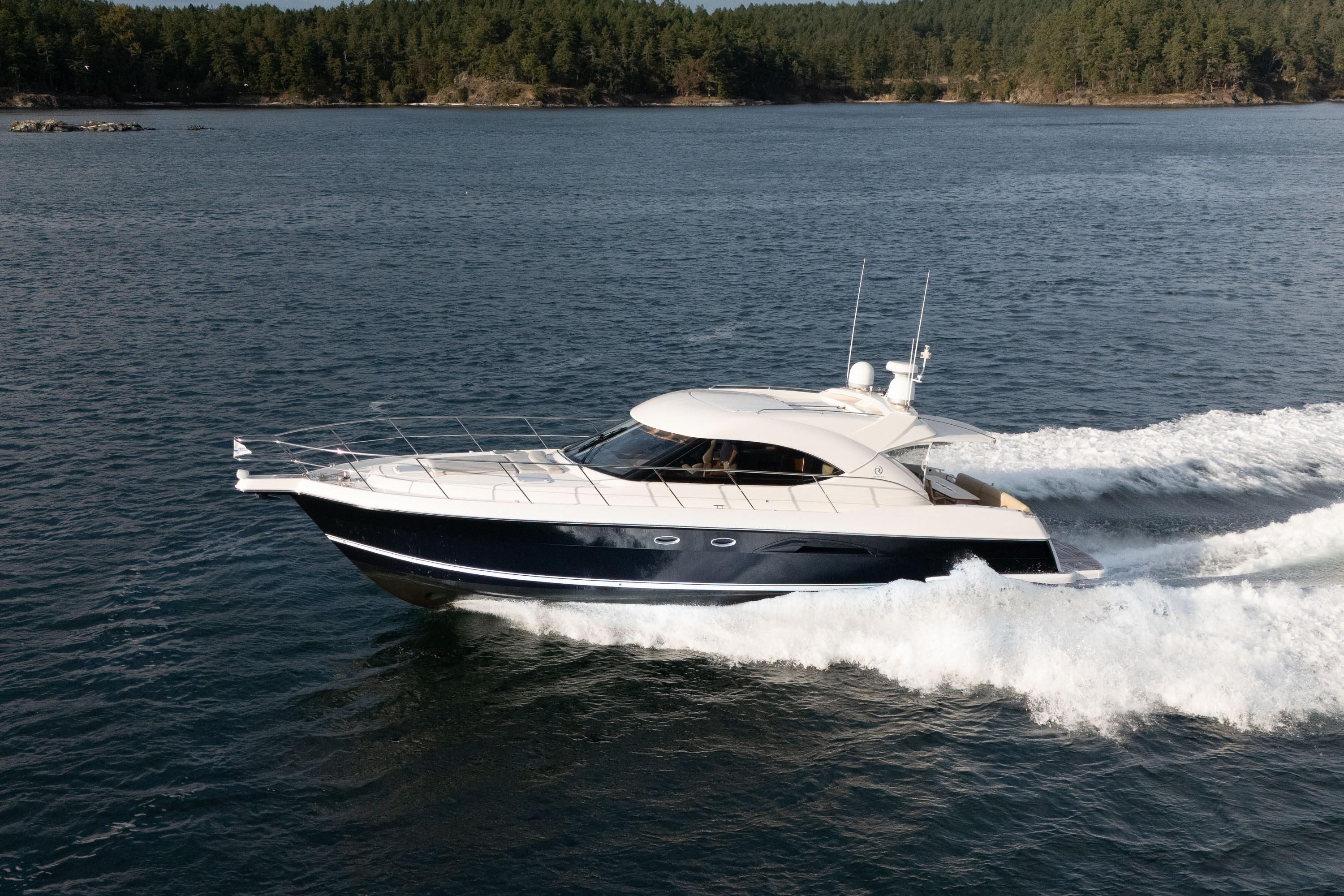2011 Riviera 5000 Sport Yacht cruising on open water, surrounded by forested shoreline.
