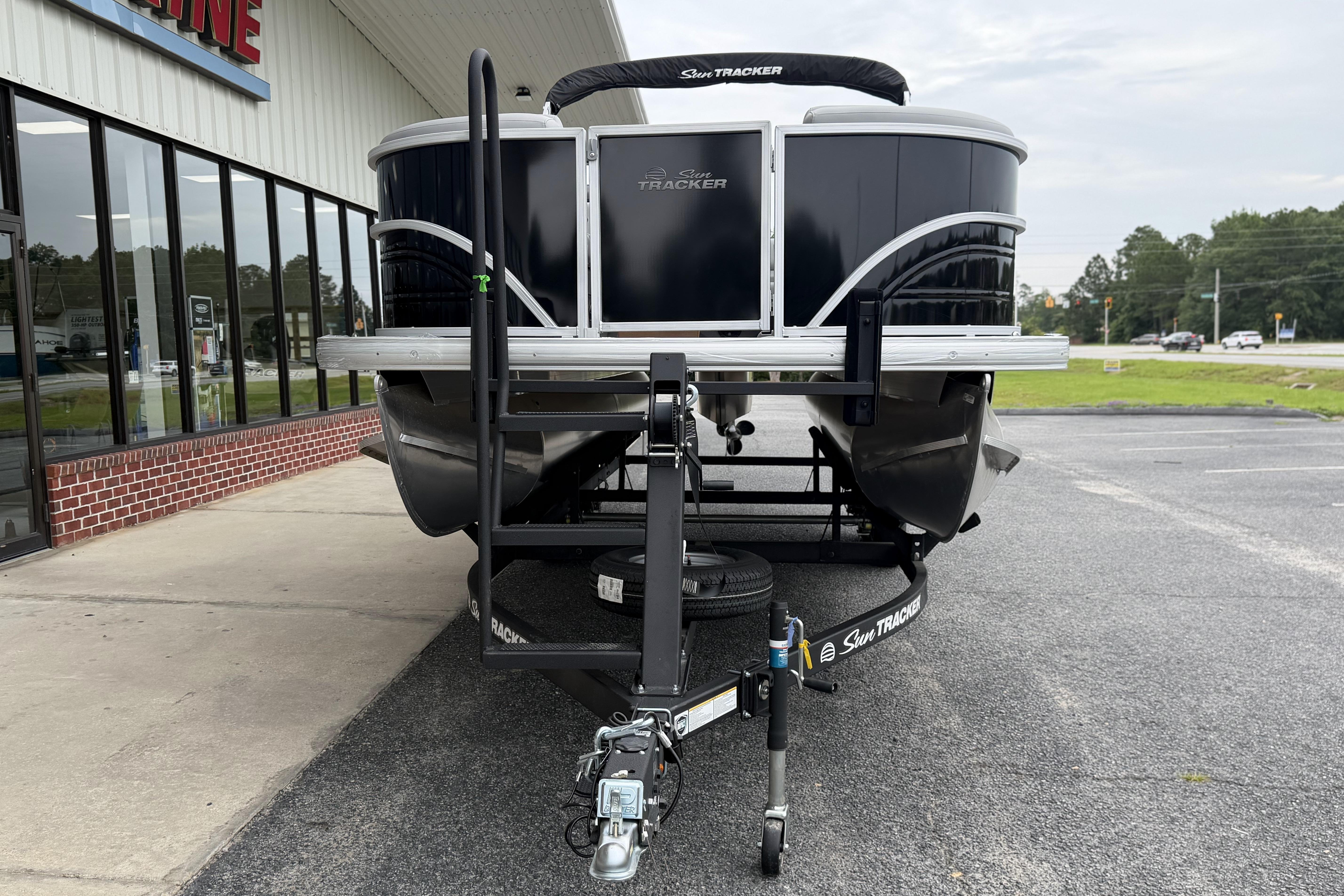 2026 Sun Tracker Party Barge 20 DLX pontoon boat on trailer outside dealership.