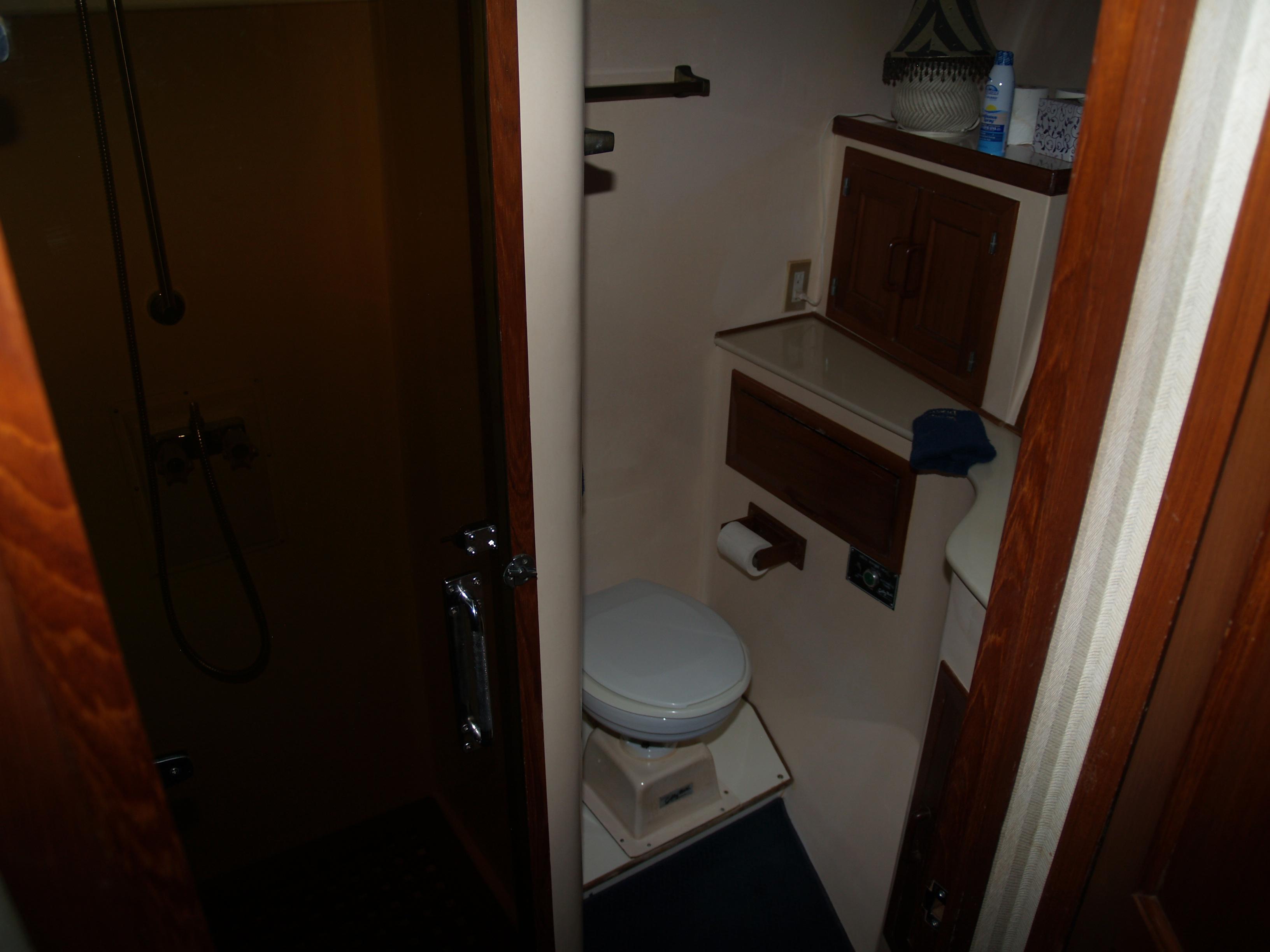 1988 DeFever 53POC yacht bathroom with shower, toilet, and wooden cabinetry.