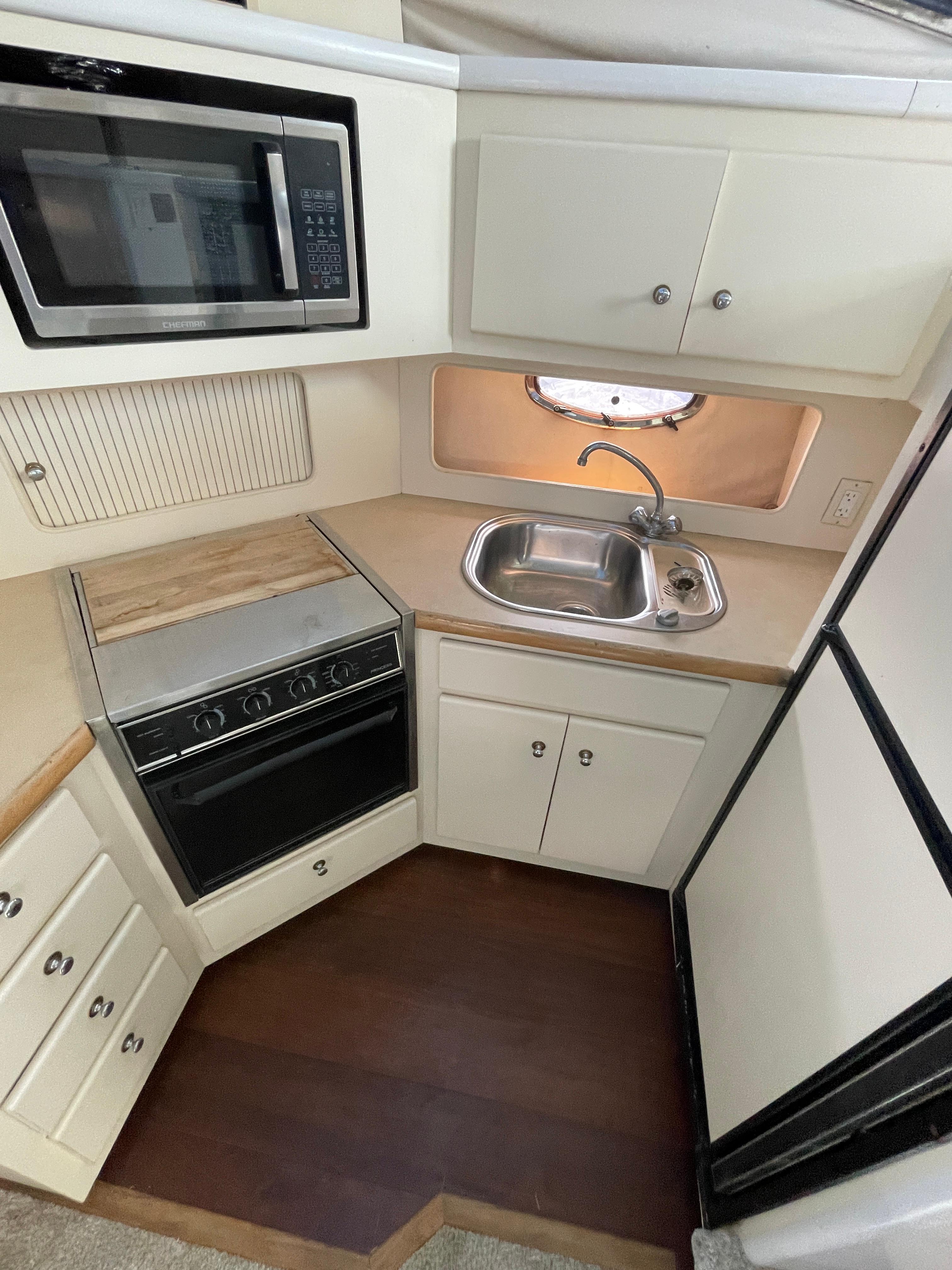 1997 Carver 405 yacht kitchen with microwave, stove, sink, and cabinets.