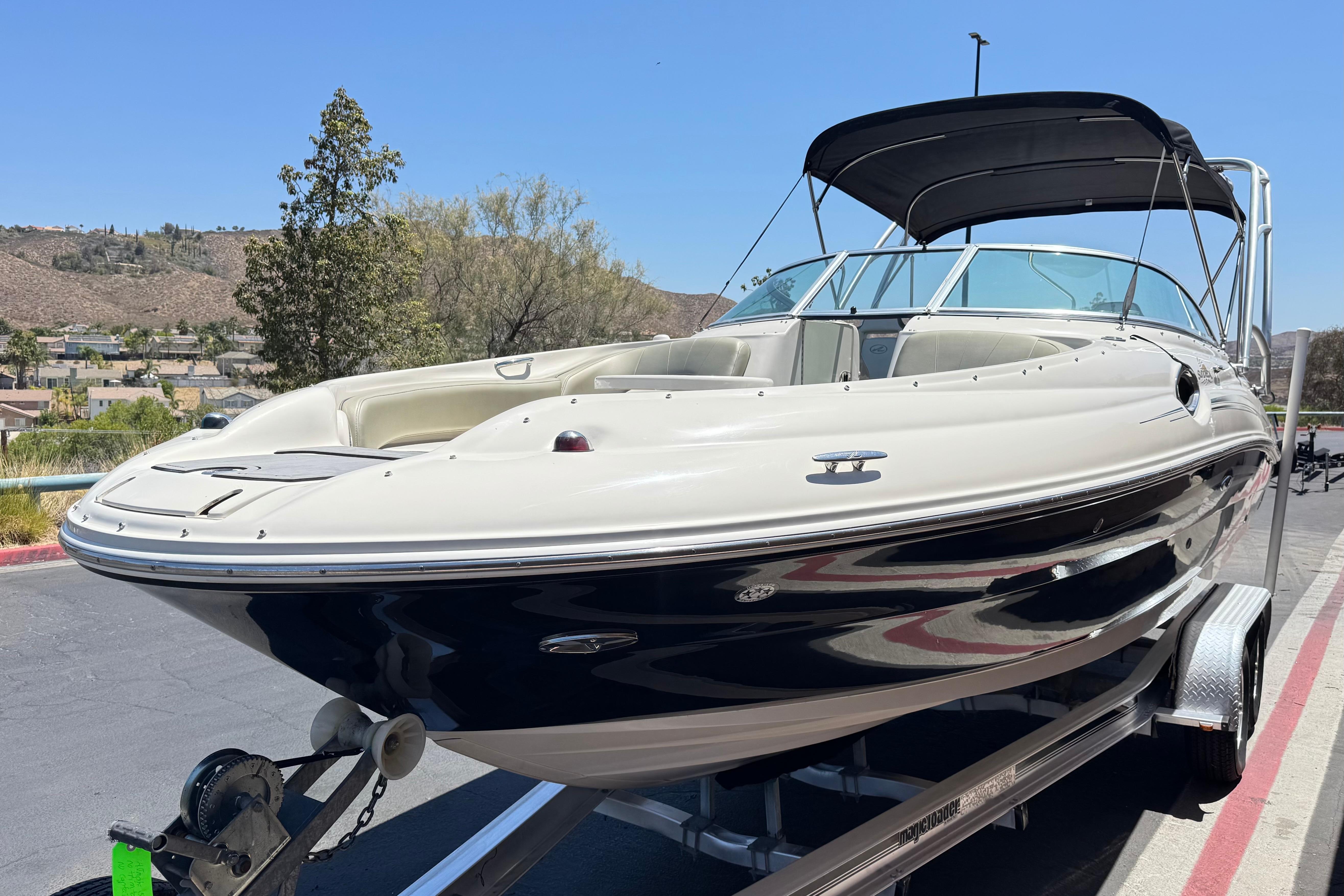 2007 Sea Ray 240 Sundeck boat on trailer, parked outdoors under clear blue sky.