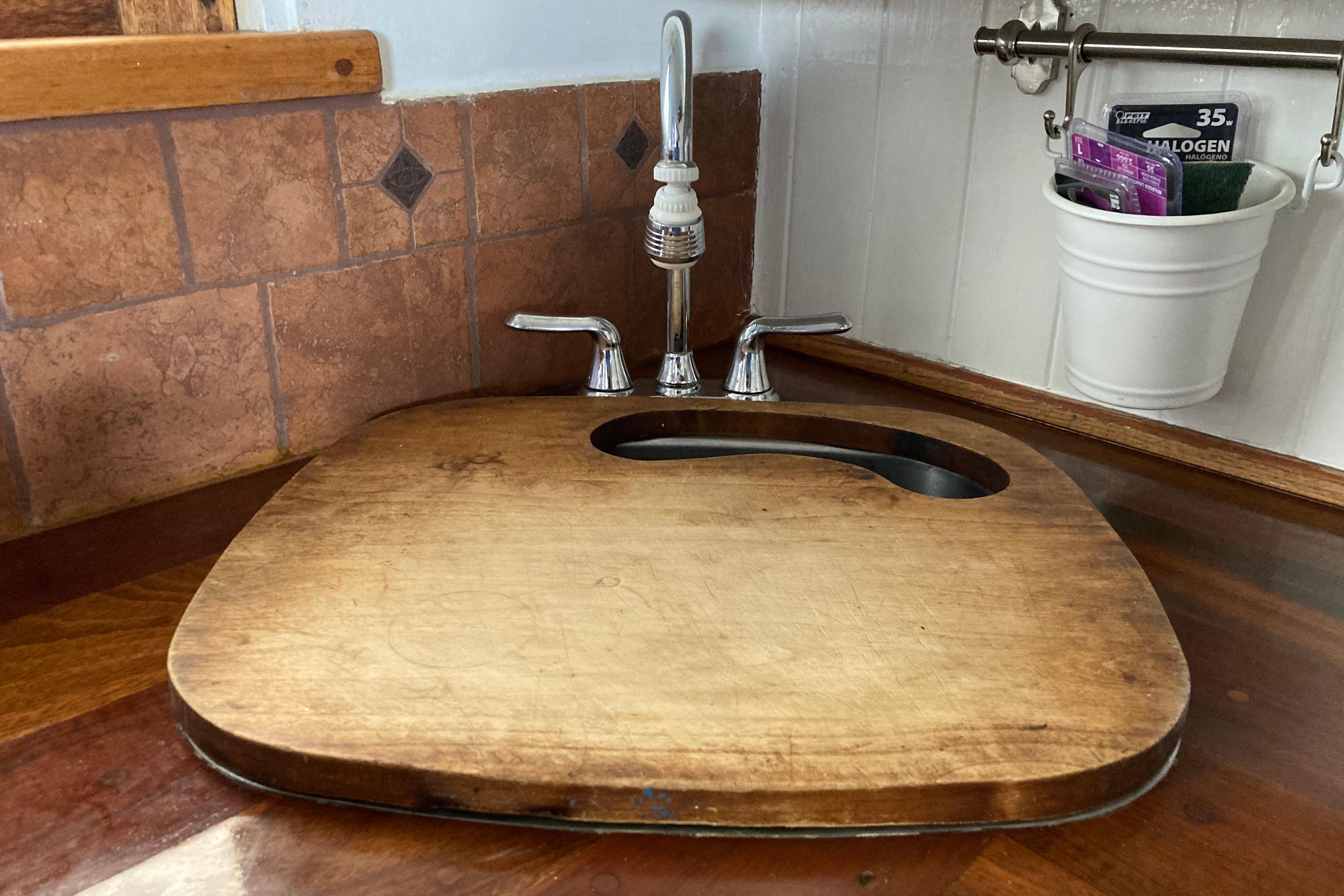 Wooden sink cover on Grenfell 42 Custom boat, 1942 model, with faucet and tiled backsplash.