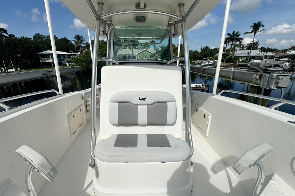 2018 Mako 284 Center Console boat interior with seating and helm, docked near palm trees.