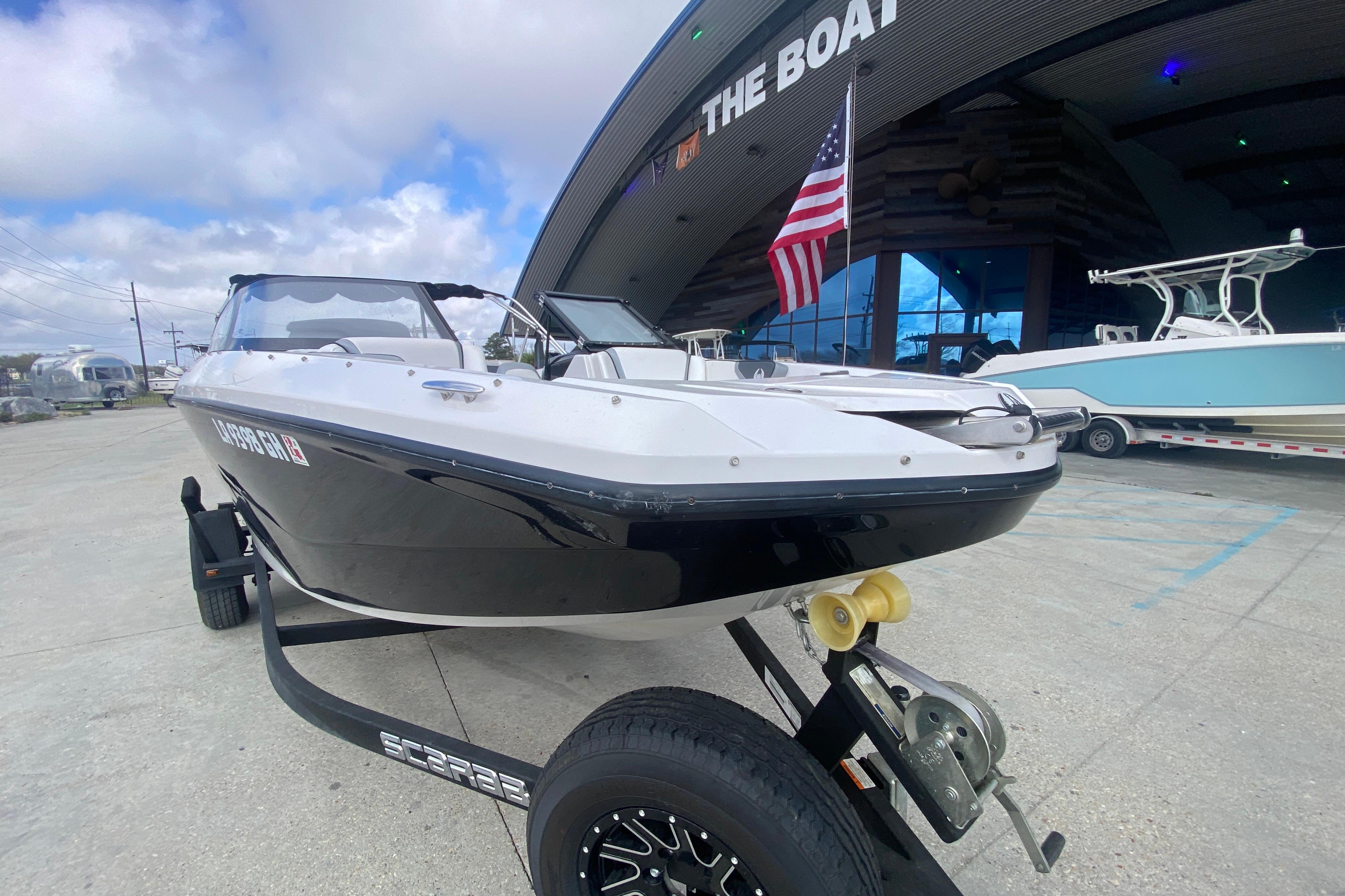 2018 Scarab 215 G boat on trailer, displayed outdoors with American flag.