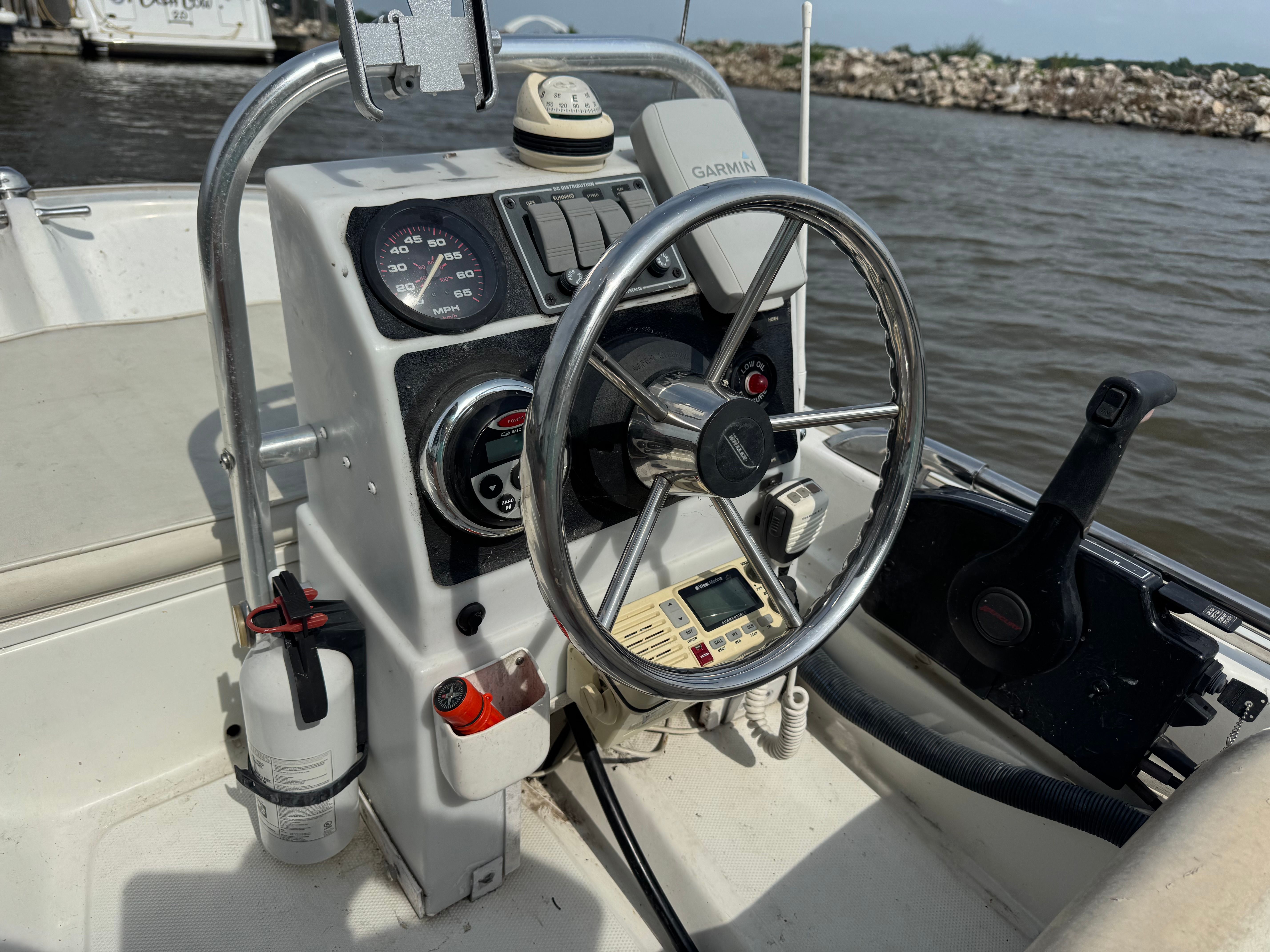The image shows a boat's helm with a steering wheel and various instruments.