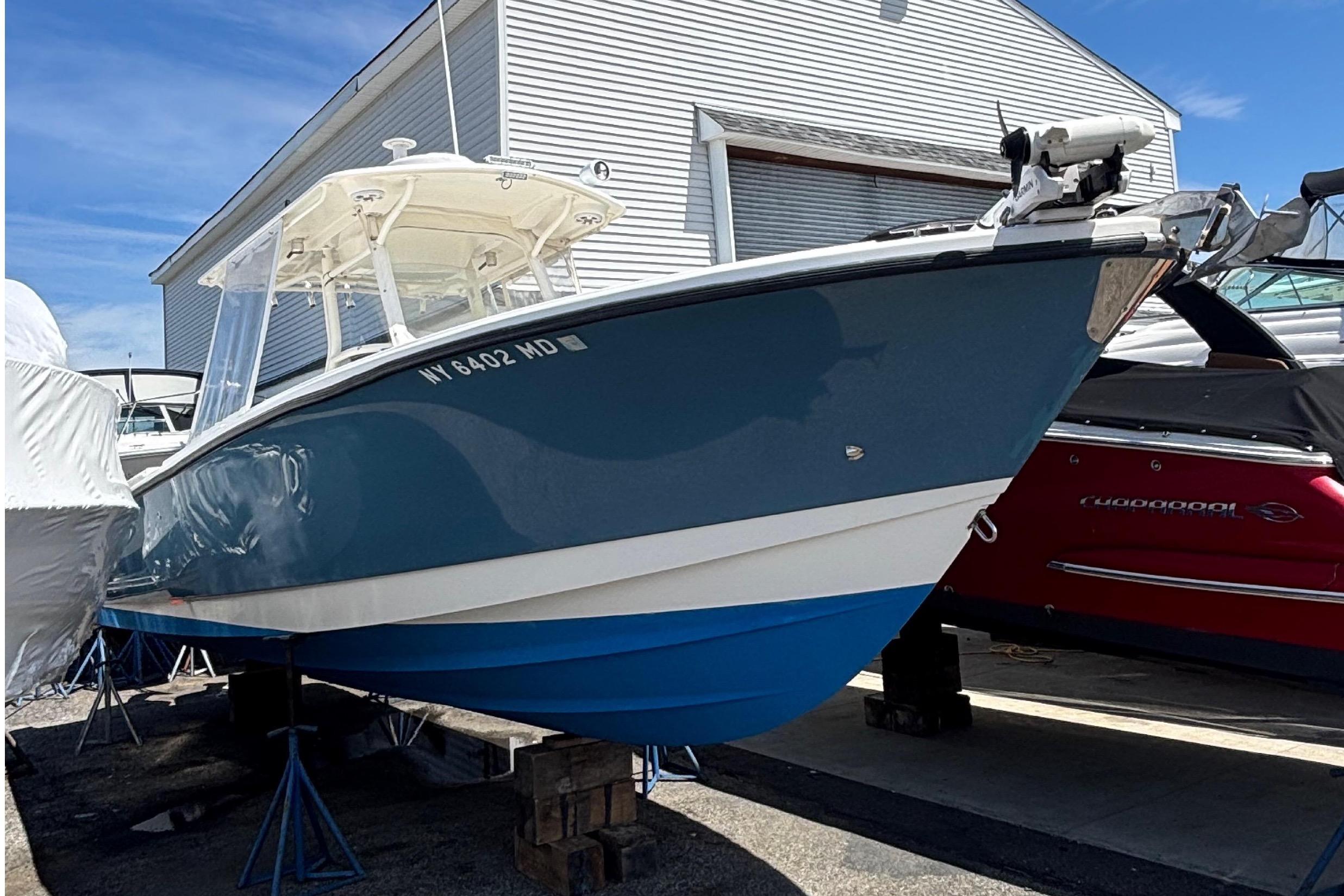A blue and white 2006 Edgewater 318CC is on a boat storage lot.