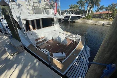 1987 Topaz 44 Flybridge yacht docked by a canal with palm trees.