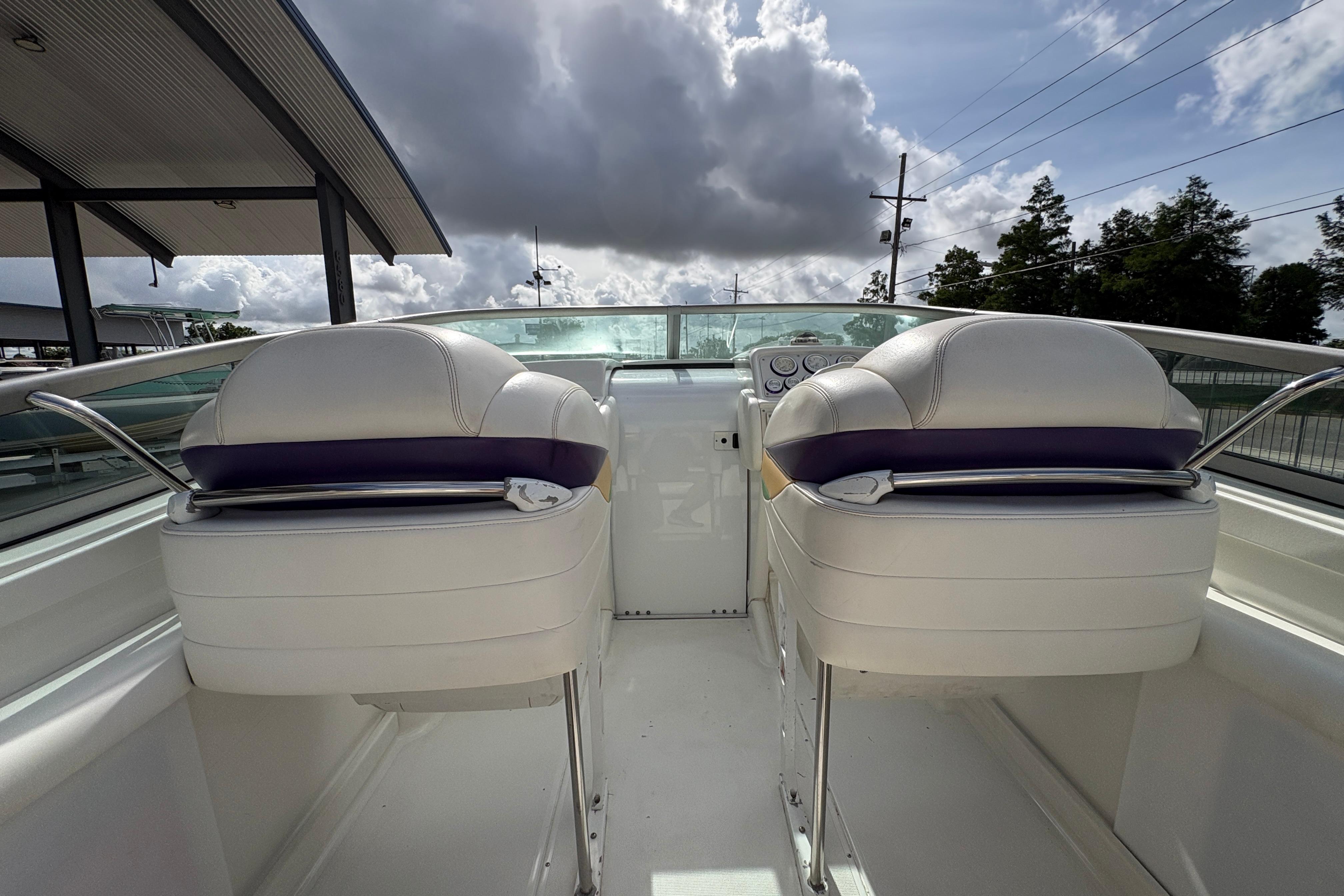 2002 Formula 292 FASTech boat interior with white seats and dashboard under cloudy sky.