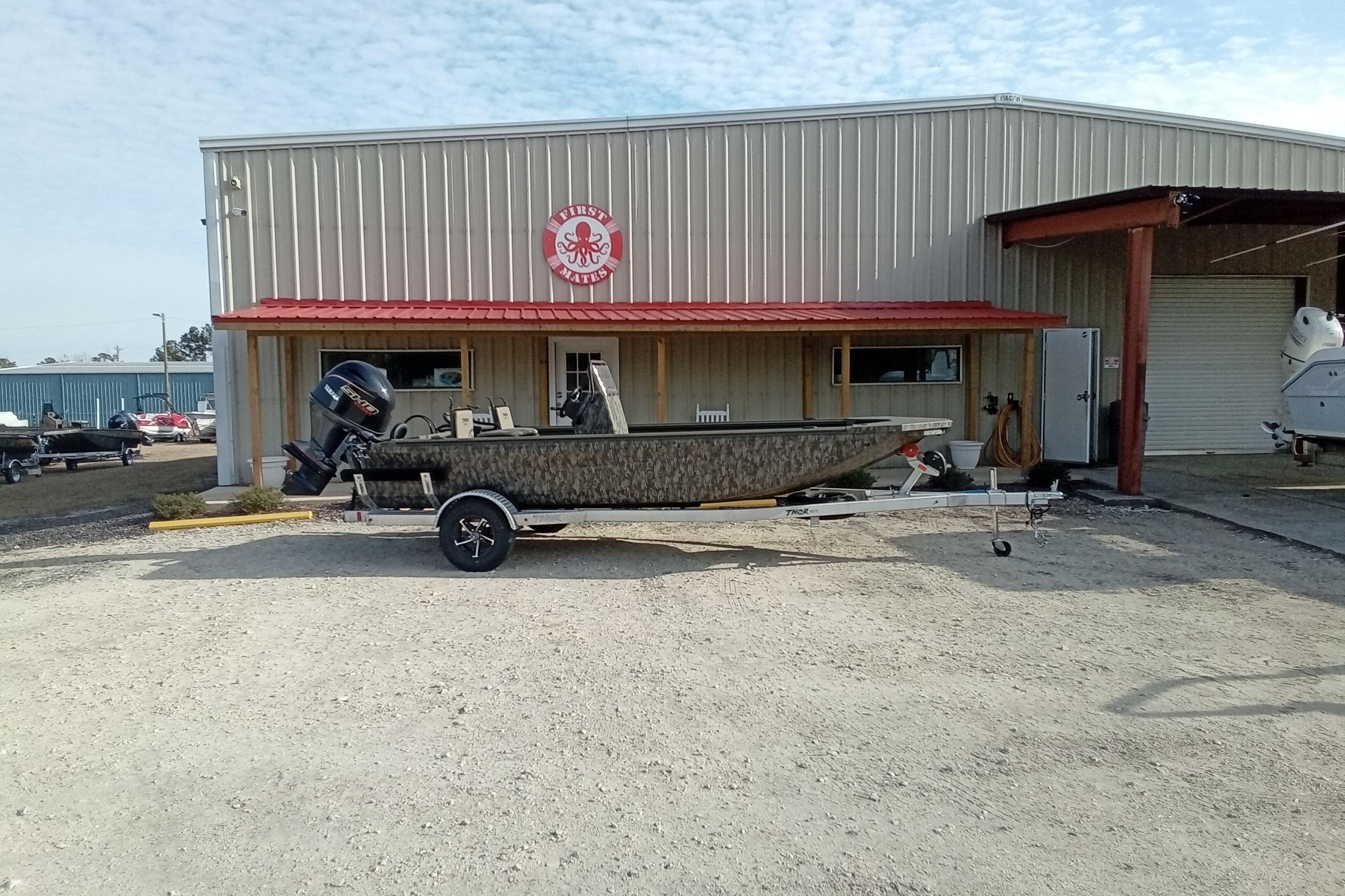 2026 Thor 1900 Low Country Elite boat on trailer outside a metal building.