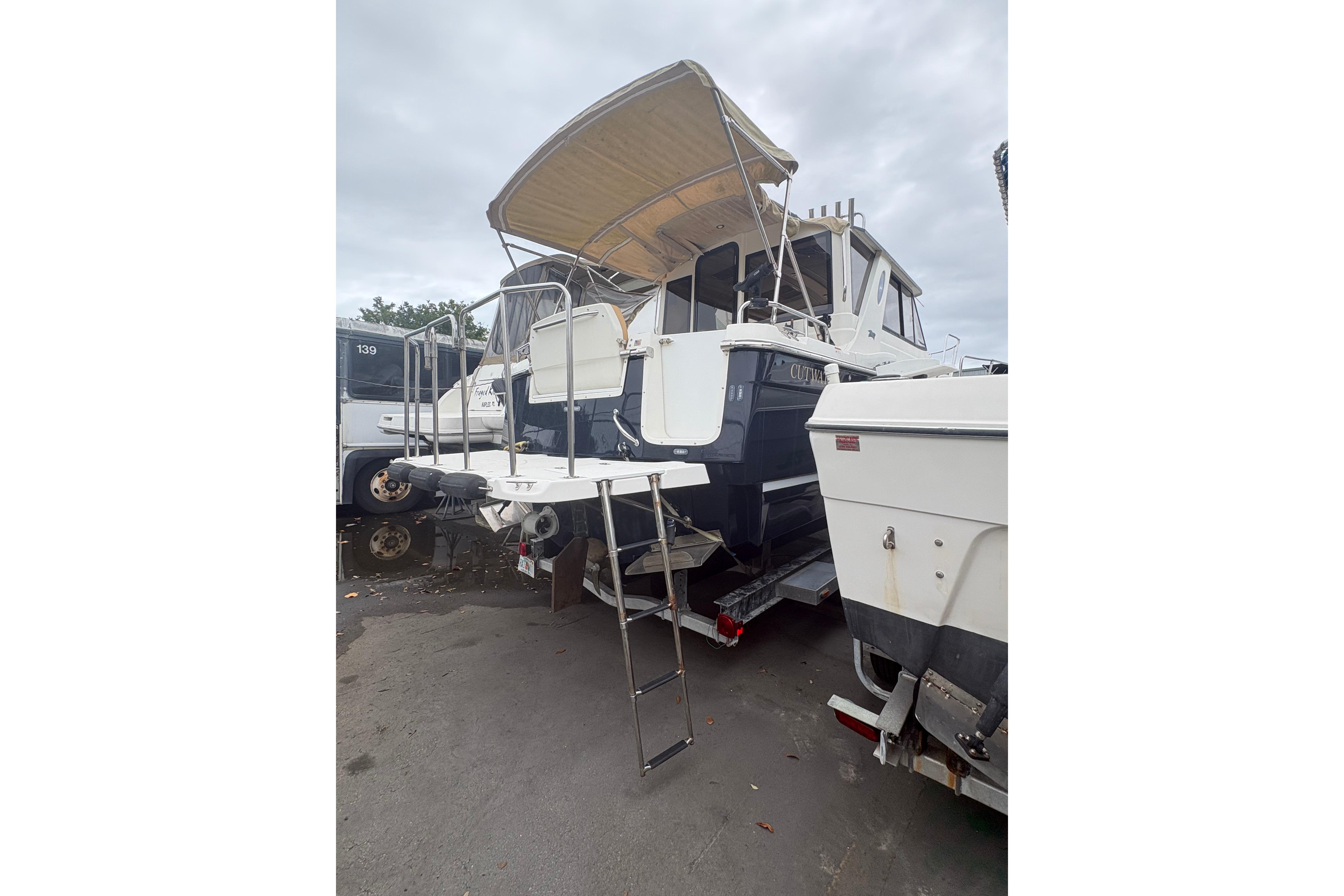 2012 Cutwater C-26 boat with canopy and ladder, parked on a trailer.