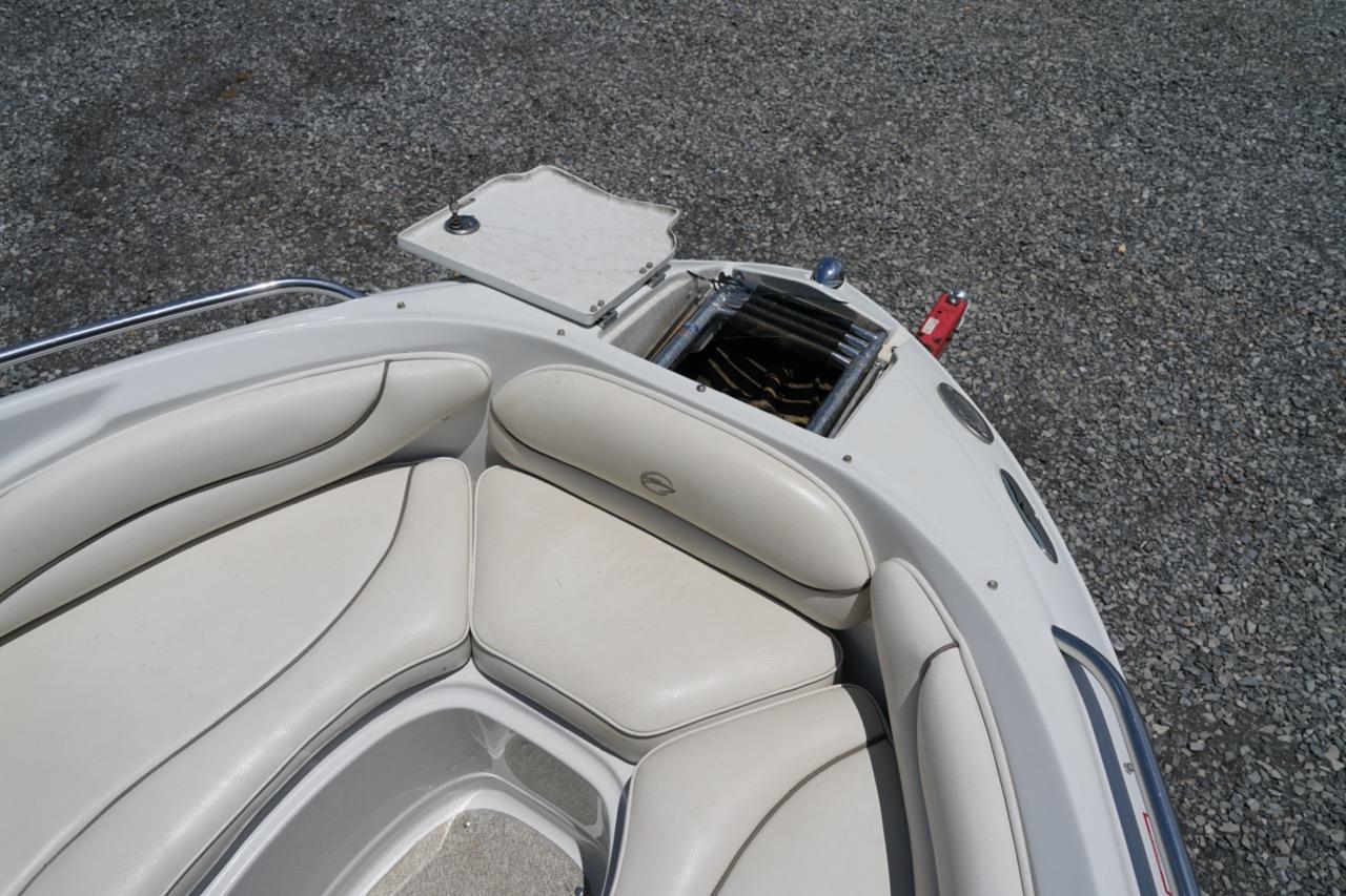 2004 Crownline 216 LS boat interior with white cushioned seating and open storage compartment.