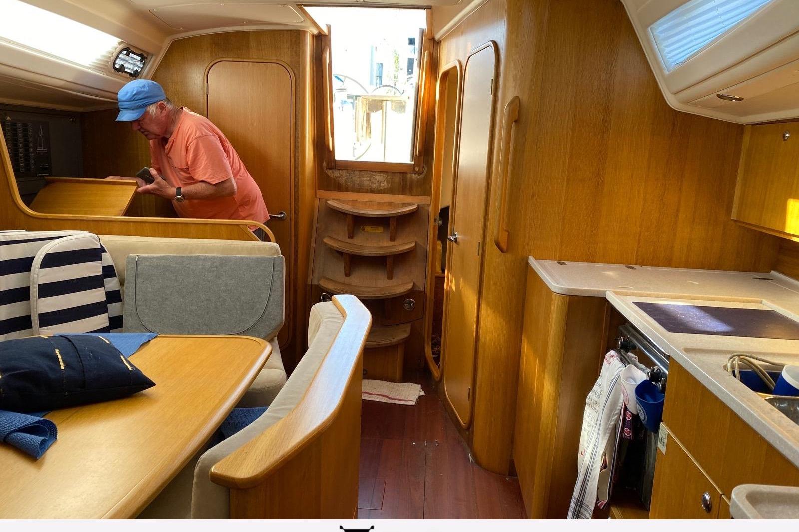 Interior of a 2010 Maxi 1300 sailboat with wooden furnishings and a person inspecting.