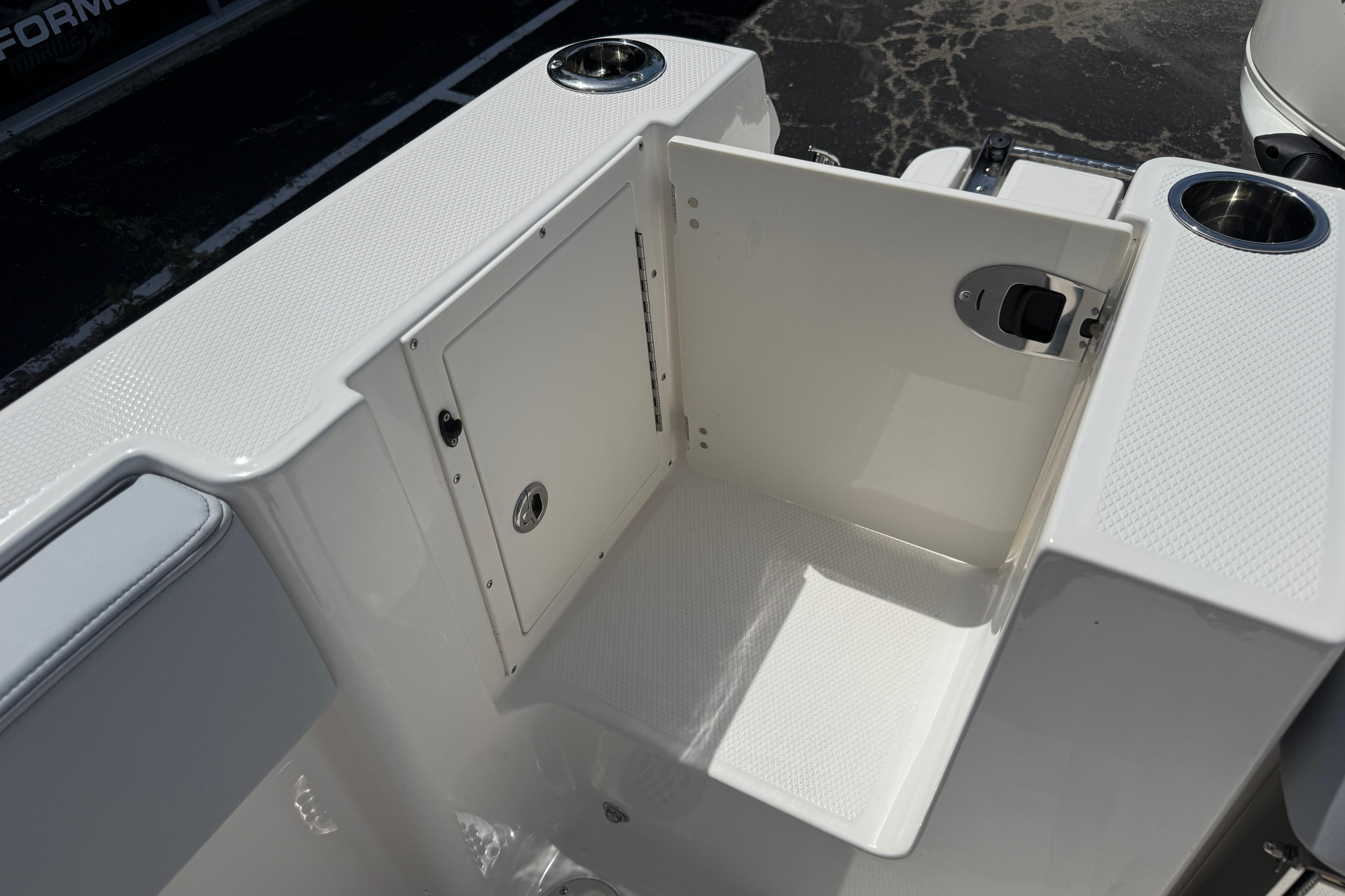 2026 Robalo R250 Center Console boat storage compartment with cup holders and textured surfaces.