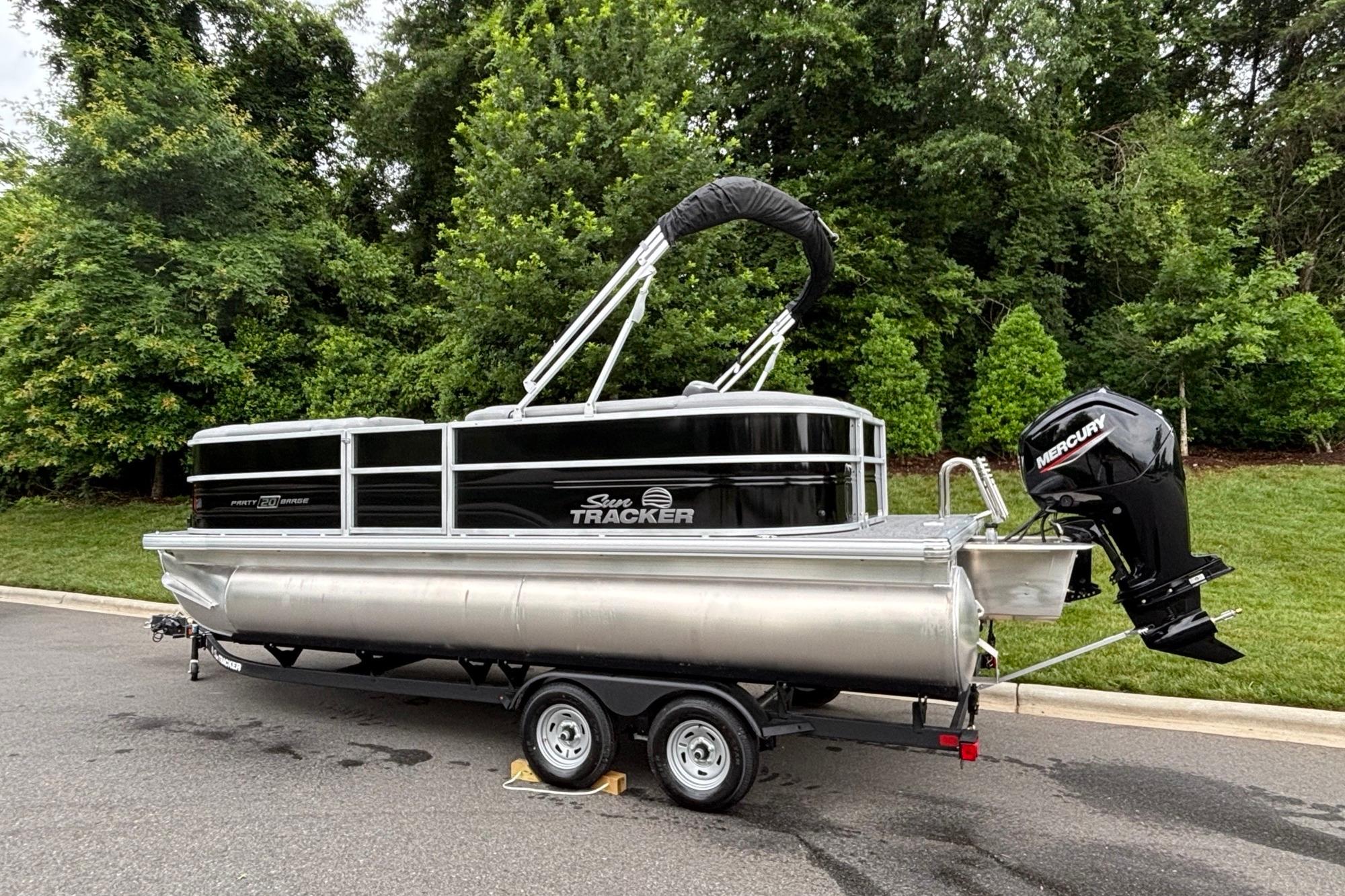 2026 Sun Tracker Party Barge 20 DLX pontoon boat on trailer, parked outdoors.