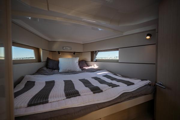 Cabin of the Beneteau Oceanis 38.1 with a cozy bed and windows.