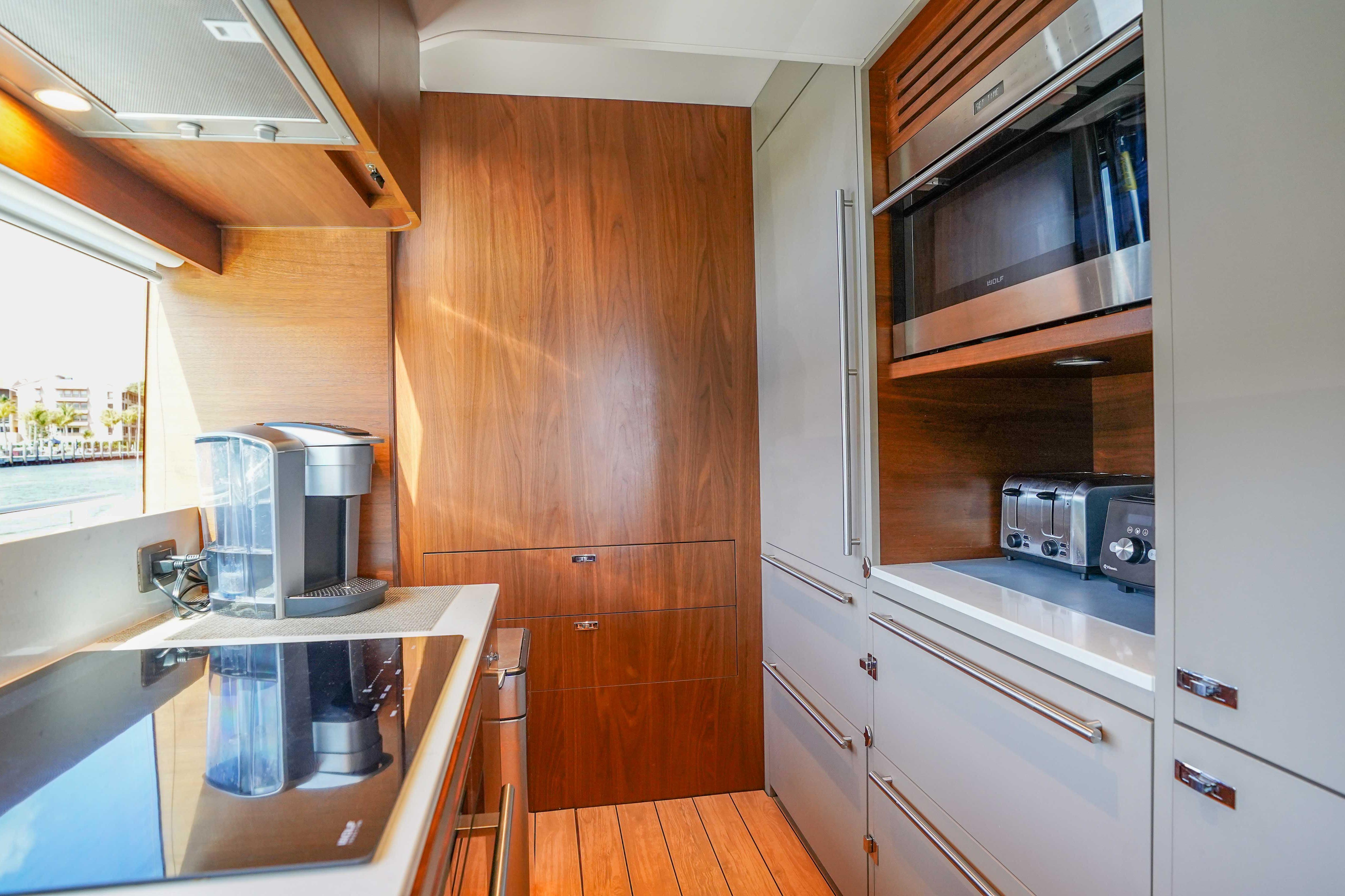 Modern kitchen interior on 2021 Princess Y85 yacht, featuring sleek appliances and wood finishes.