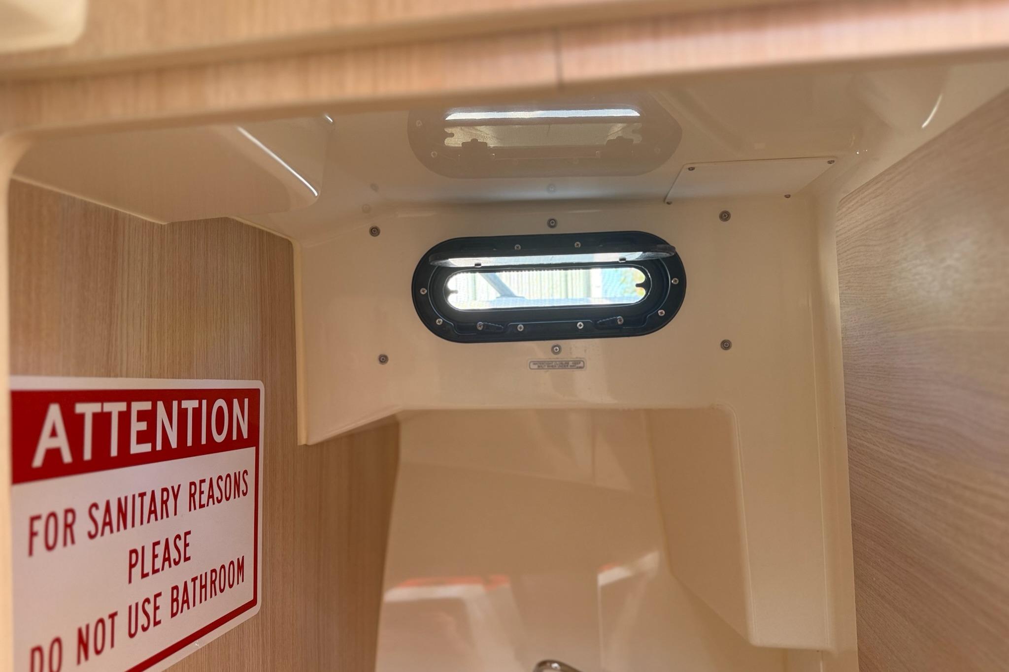 Interior of 2024 Bayliner Trophy T25 Pilothouse with a warning sign about bathroom use.