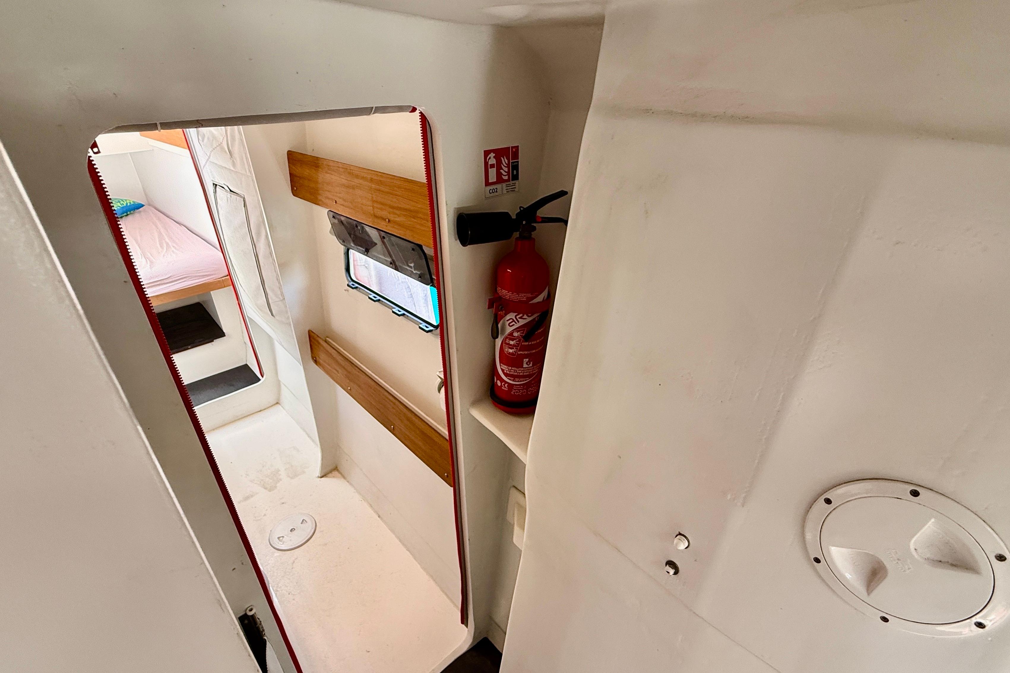Interior of 2020 Marsaudon Composites TS 42 catamaran, featuring cabin entrance and fire extinguisher.