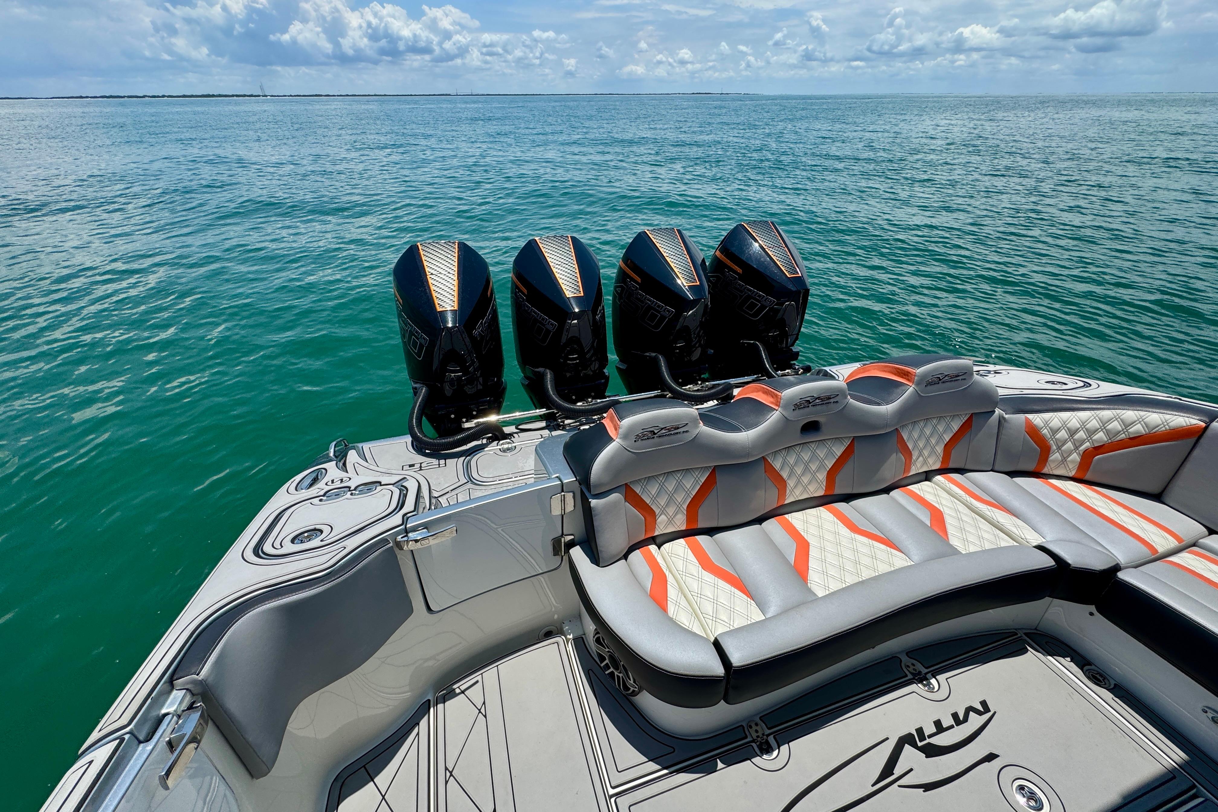 Luxury MTI V42 boat with quad engines and stylish seating on open water.