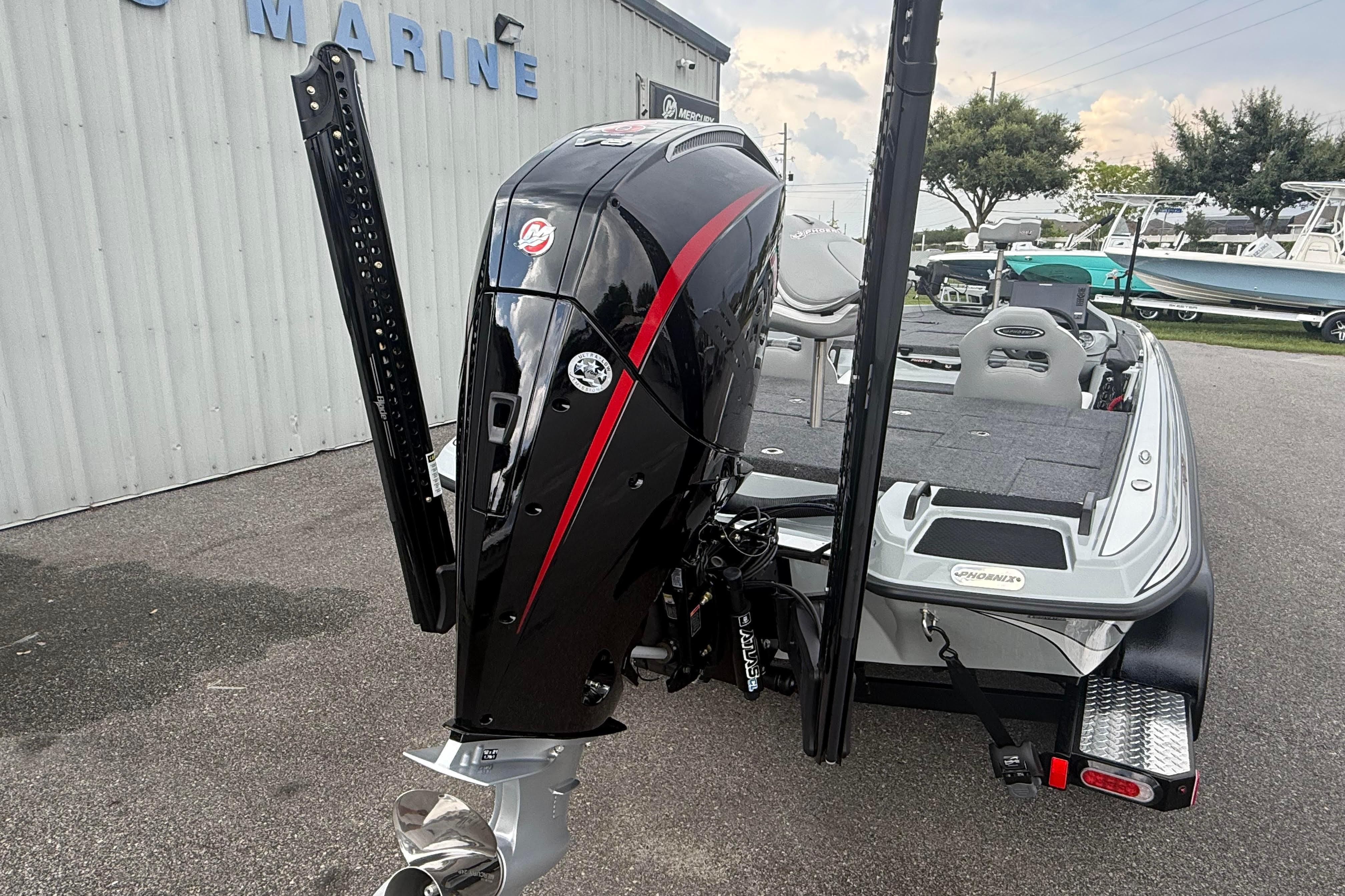2027 Phoenix 921 Elite X II boat with powerful outboard motor, parked near marine facility.