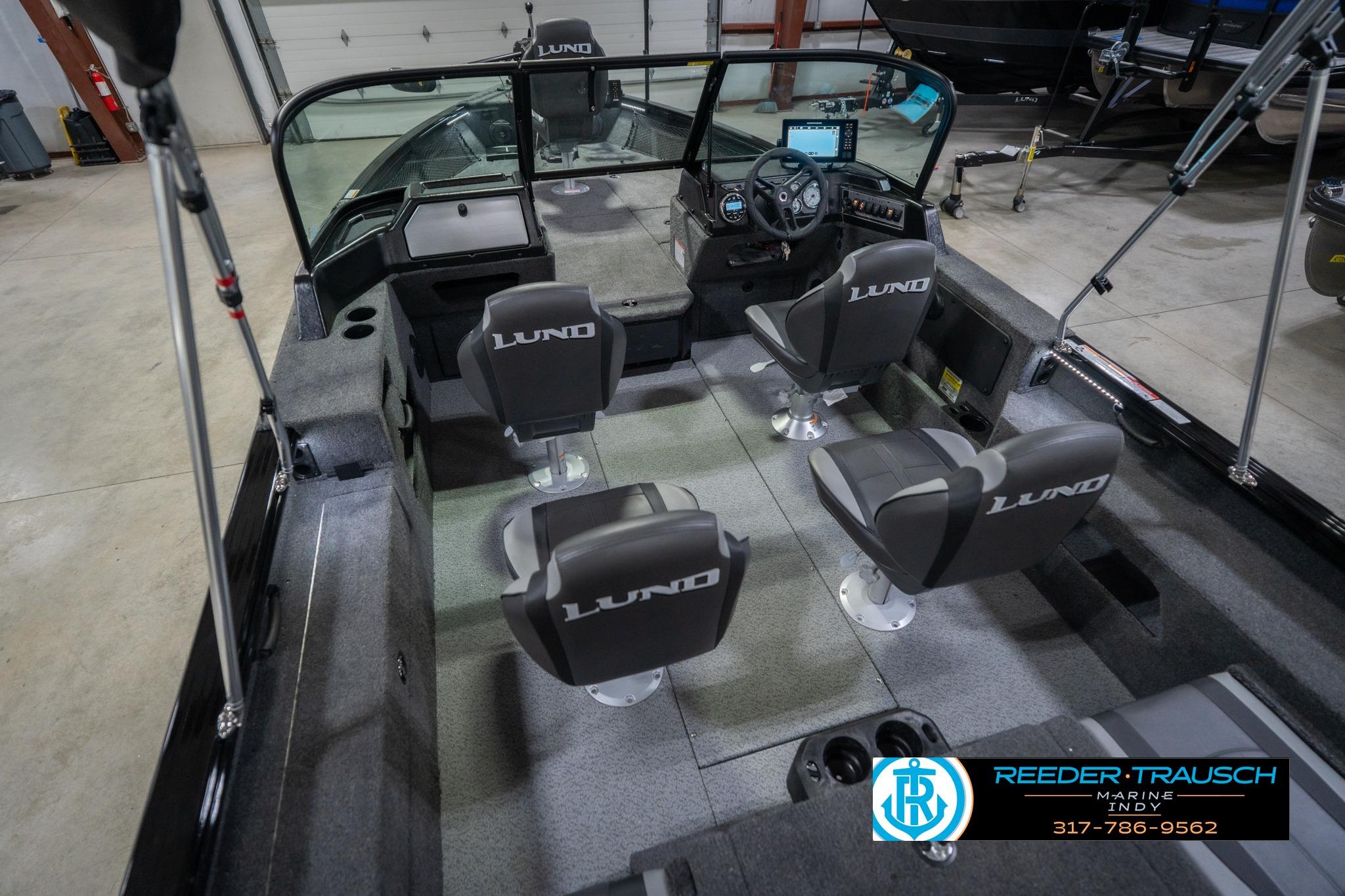 2026 Lund 2075 Impact XS boat interior with seating and dashboard, displayed in a showroom.