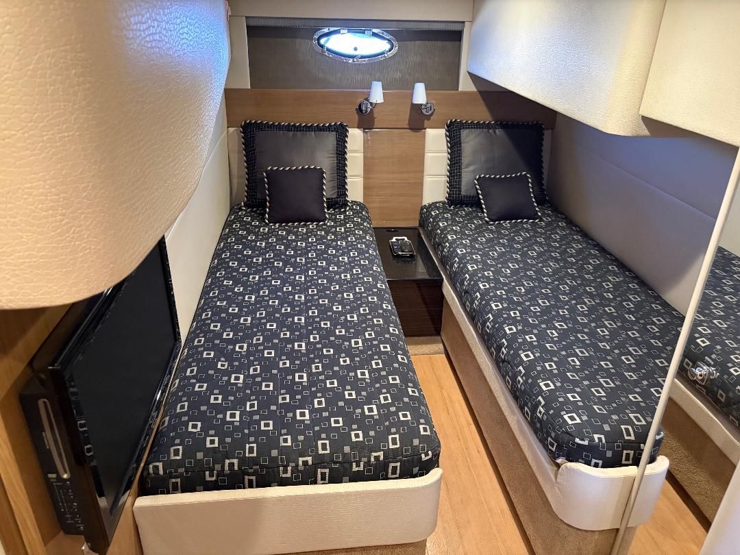 Two single beds in a sleek cabin with wooden flooring and a small window.