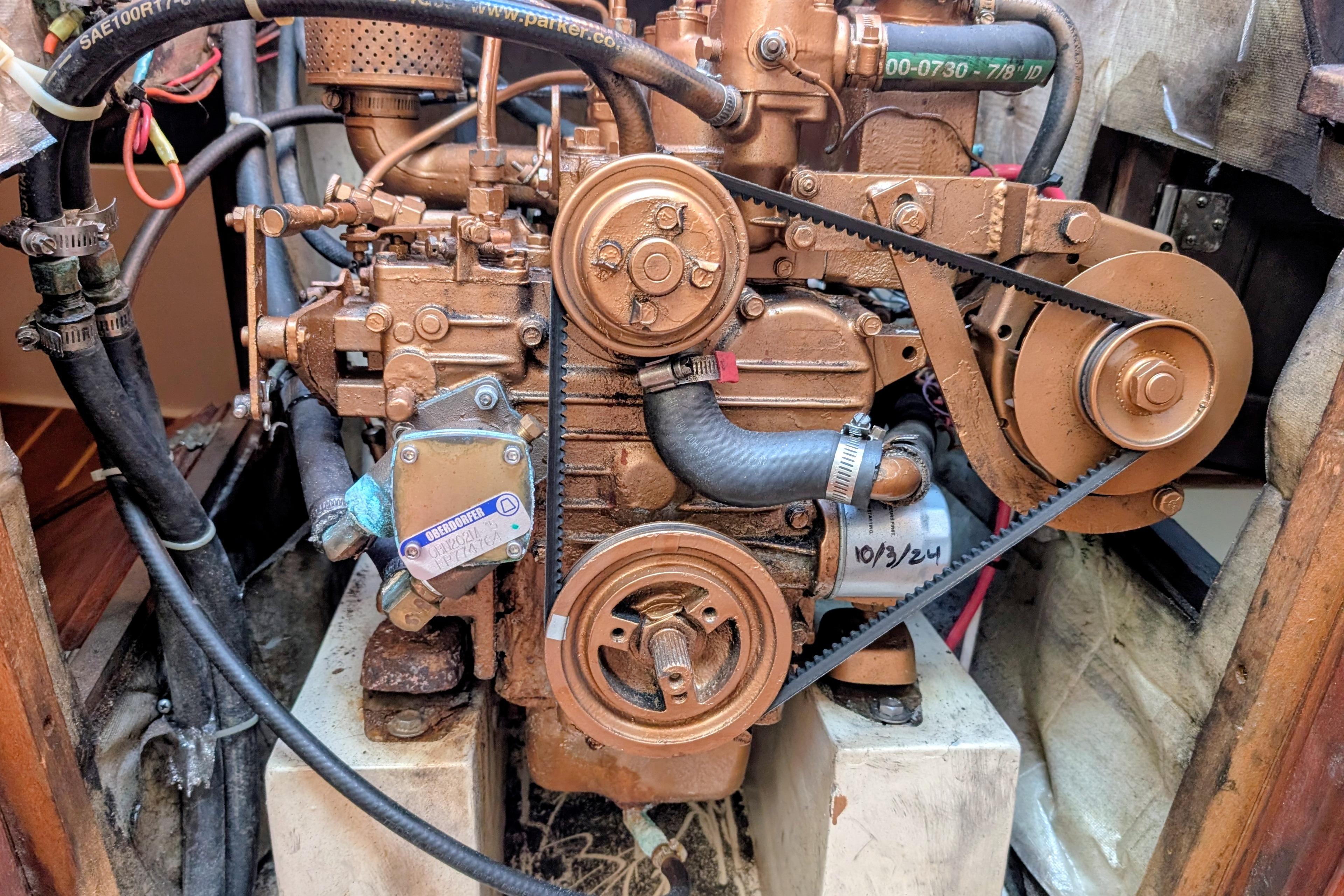 Engine of a 1989 Catalina 34 sailboat, showcasing belts and hoses in a compact space.