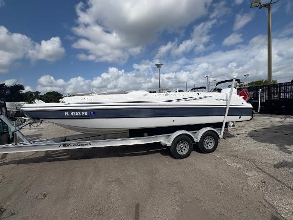 2014 Hurricane SunDeck Sport 232 OB boat on trailer under cloudy sky.