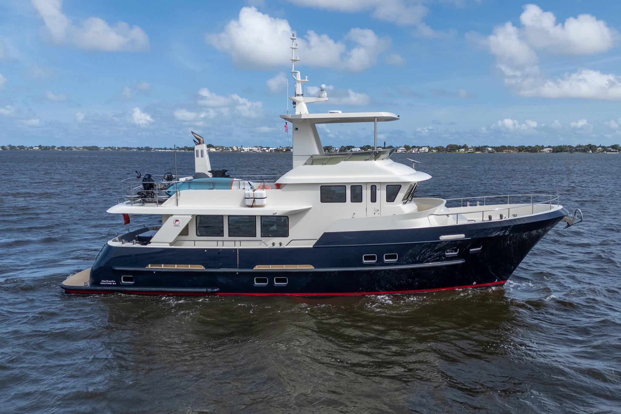 2022 Alm Trawler Delfino 64 yacht cruising on open water under a clear blue sky.
