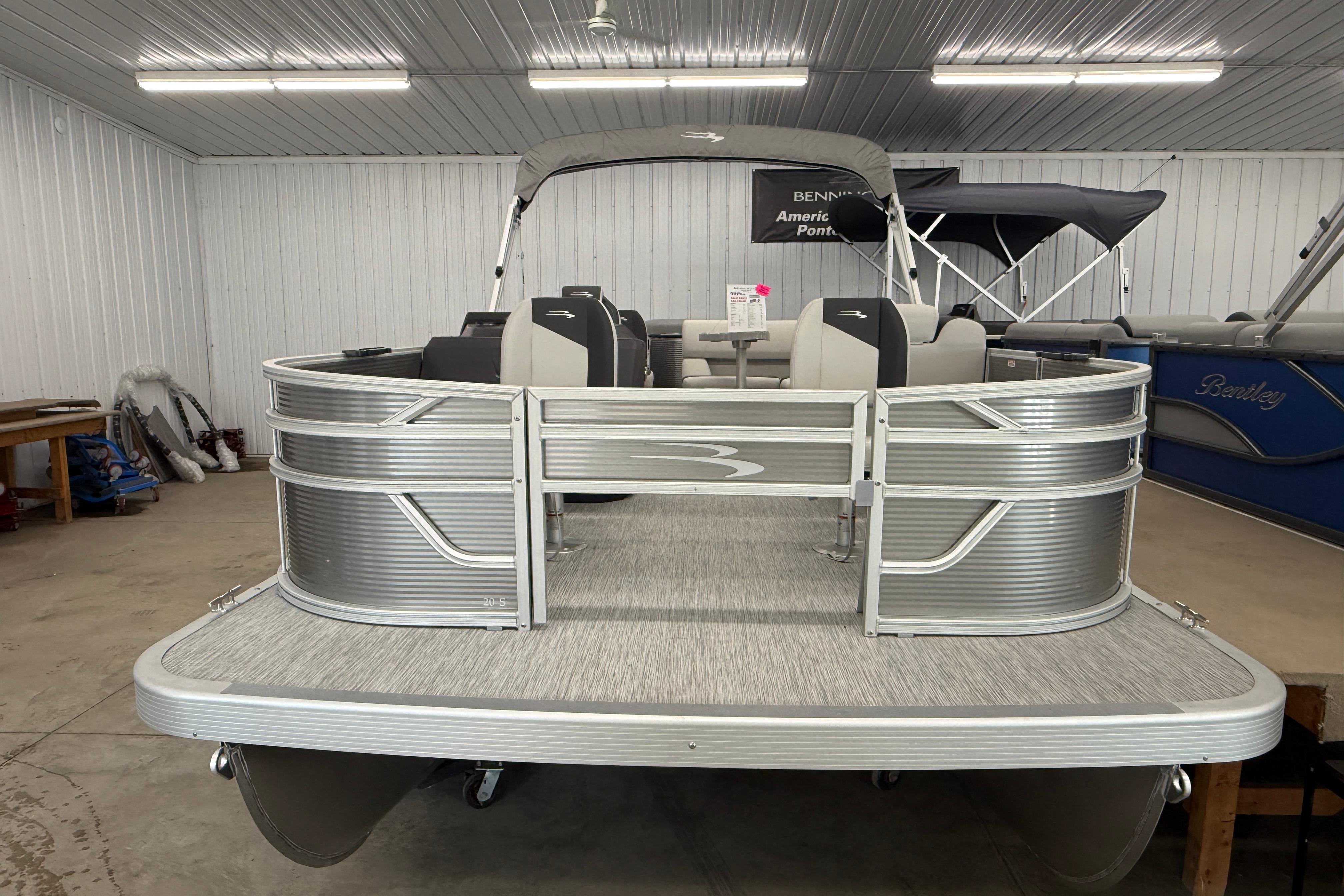 2026 Bennington 20 SF pontoon boat in showroom, featuring sleek silver design and spacious seating.