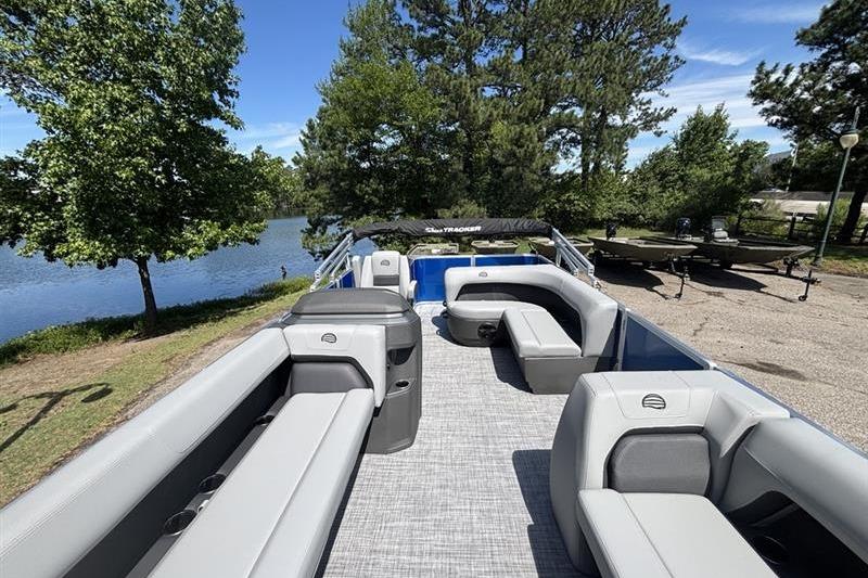 2026 Sun Tracker Party Barge 18 DLX pontoon boat with spacious seating by a serene lake.