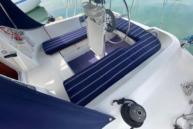 Cockpit of 1992 Beneteau First 310 sailboat with striped cushions and steering wheel.