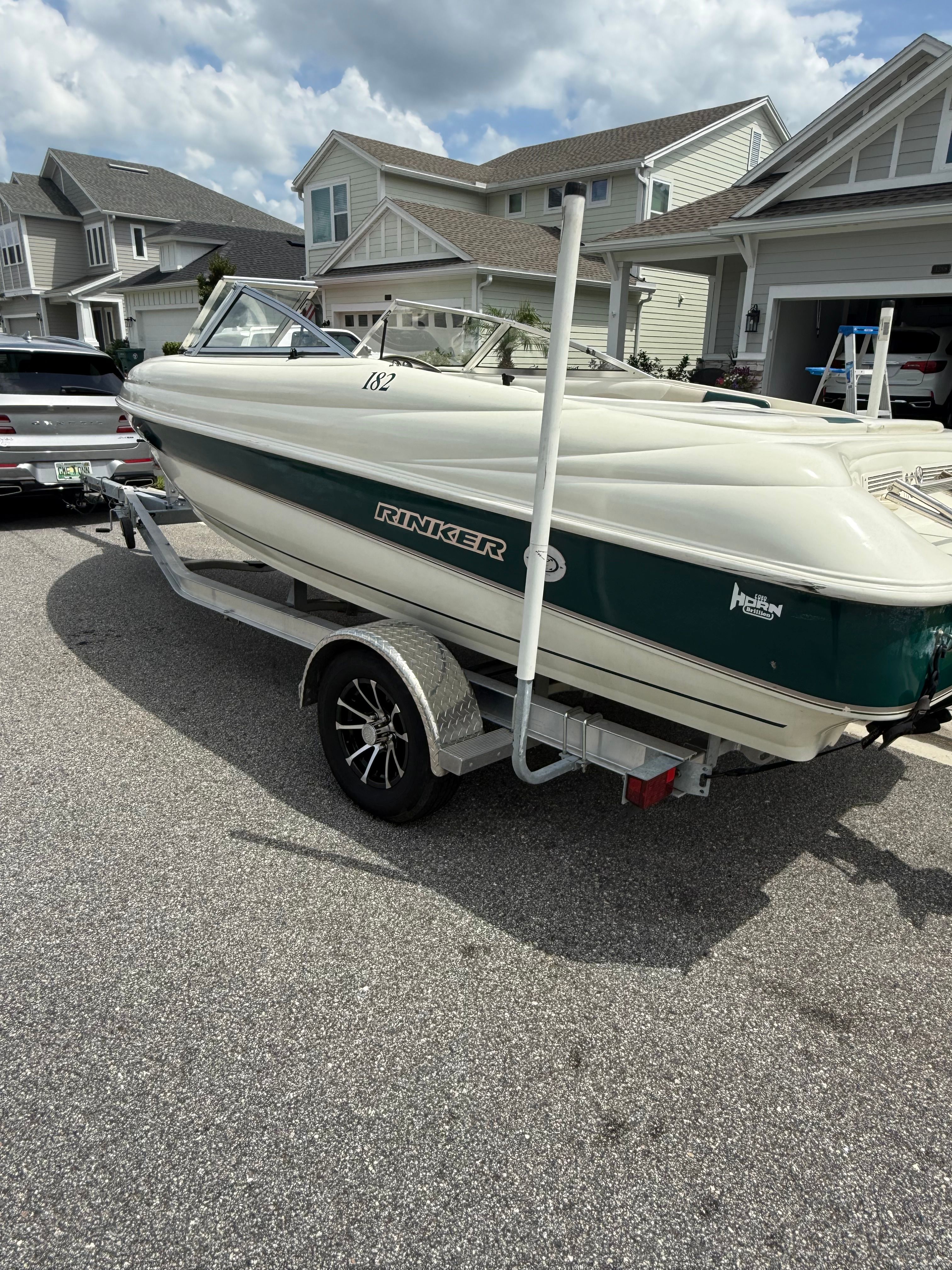 A 1998 Rinker Captiva boat on a trailer in a residential neighborhood.
