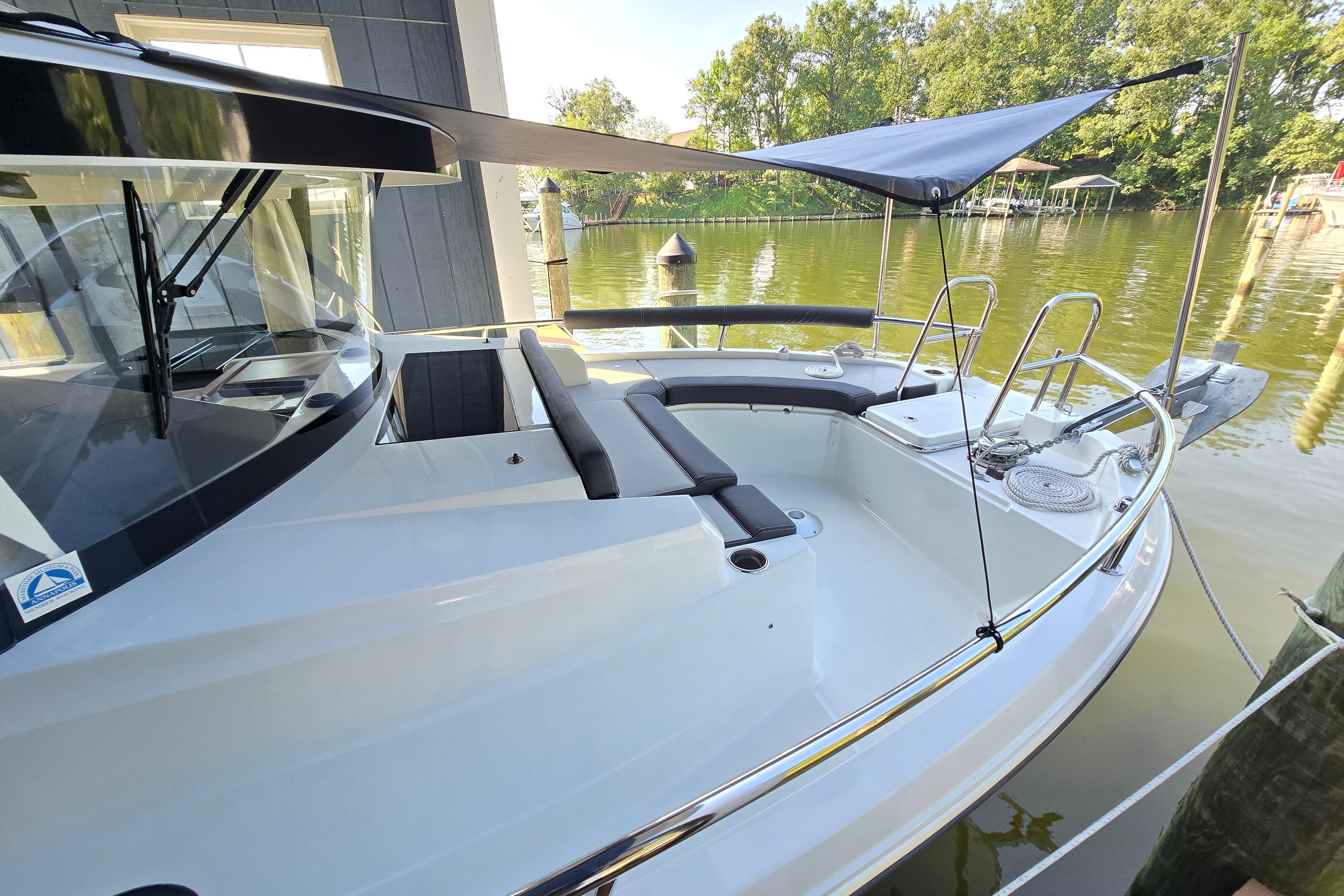 The boat is a 2023 Jeanneau NC Sport 895, docked on the water with a sunshade.