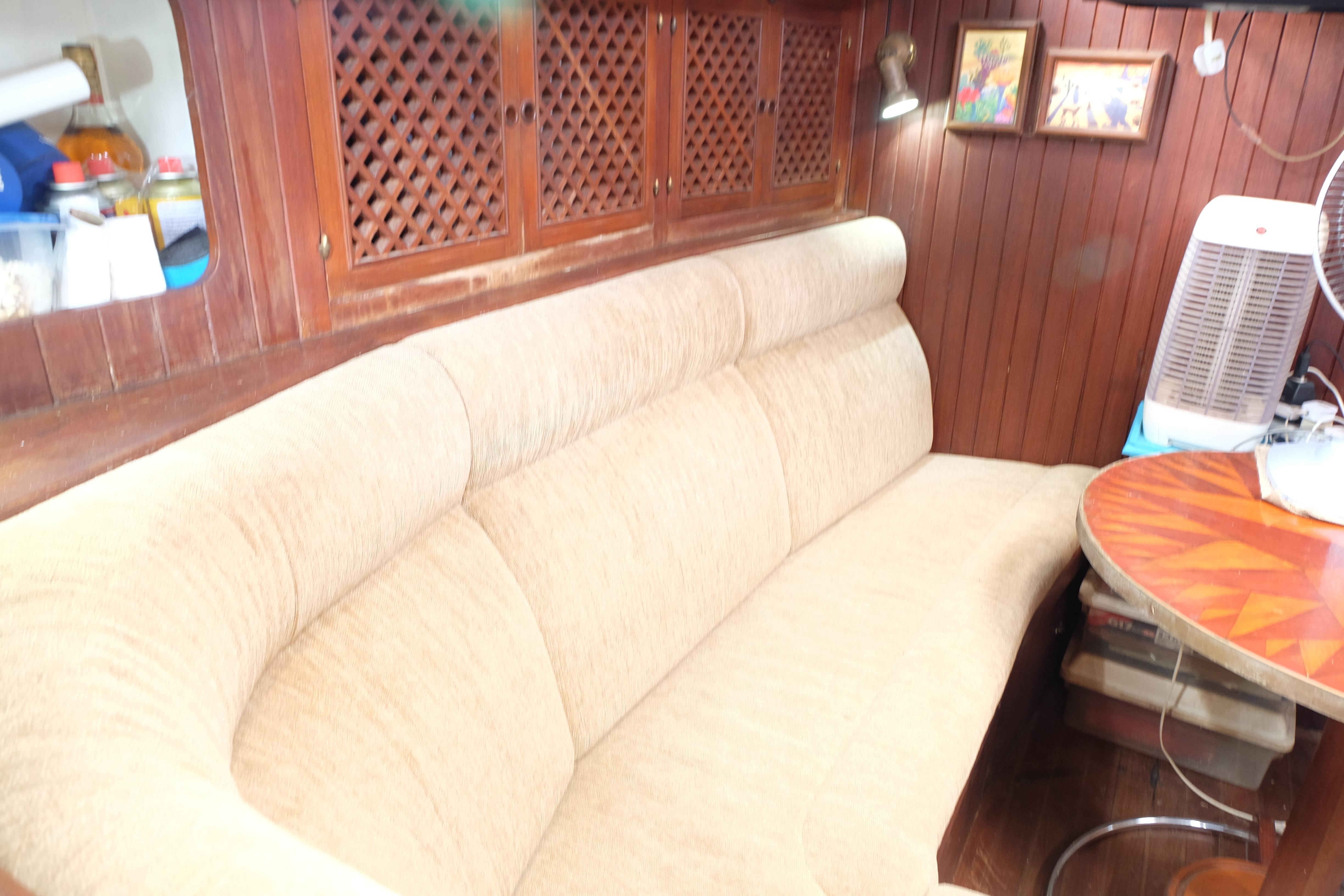Cozy 1979 Westwind 35 yacht interior with beige sofa, wooden cabinets, and decorative artwork.